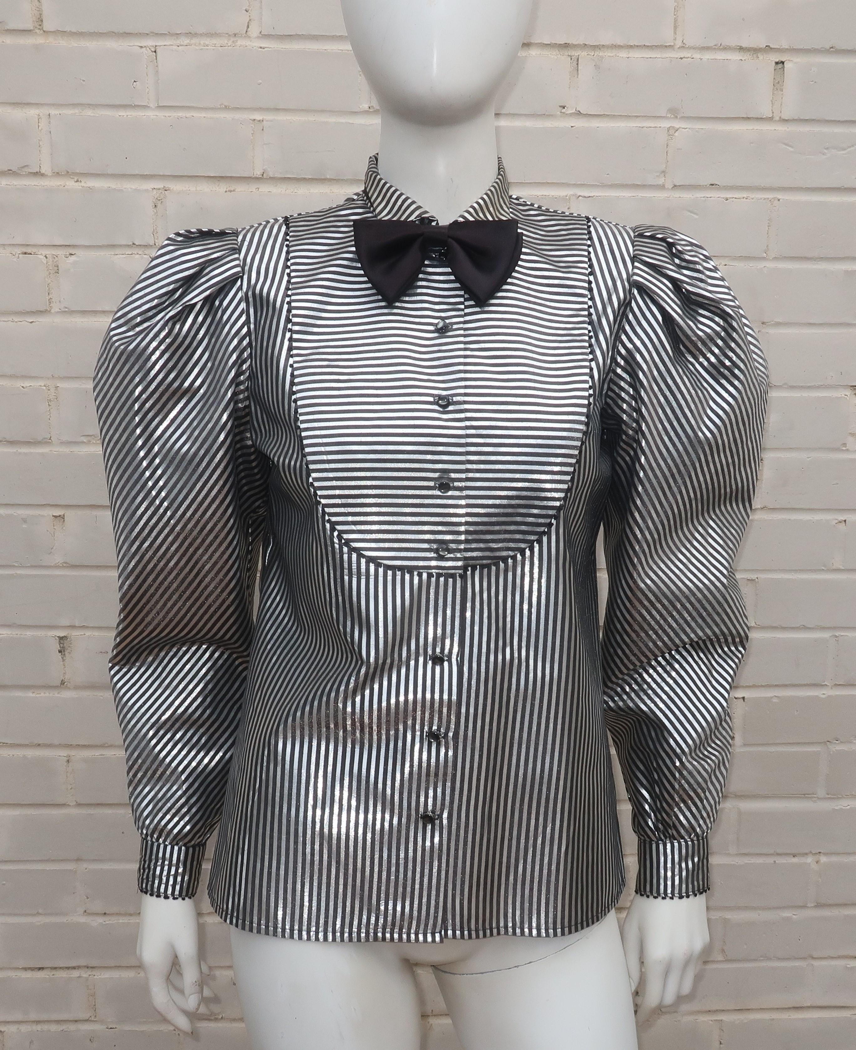 C. 1980 A. J. Bari black and silver lamé metallic top with tuxedo styling including a bib detail at the bodice and detachable bow tie.  It buttons down the front and at the rick rack edged cuffs.  The pleated upper sleeves and strong shoulder