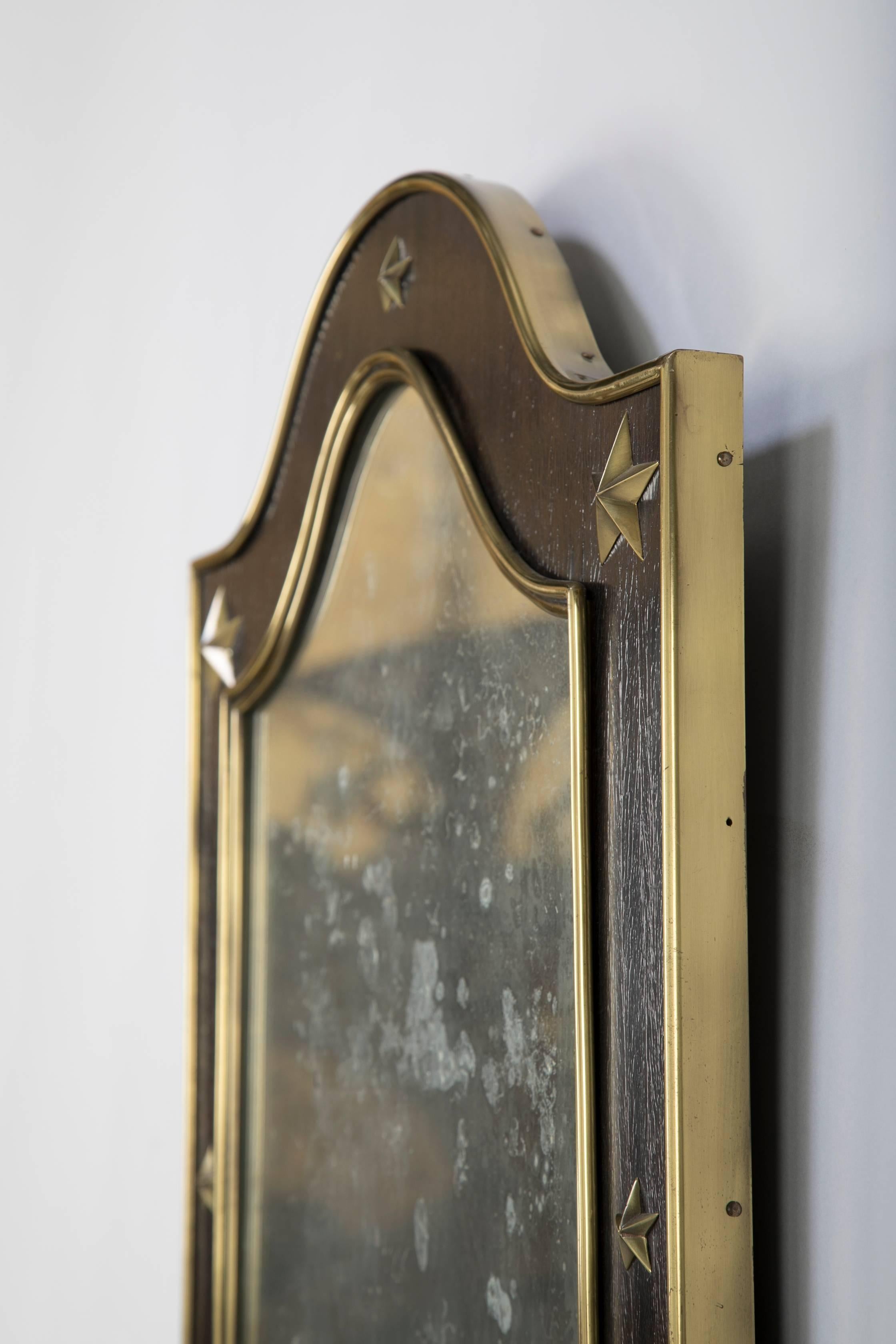 Ein Jacques Adnet Spiegel aus Holz und Messing mit dekorativen Messingsternen im Rahmen.