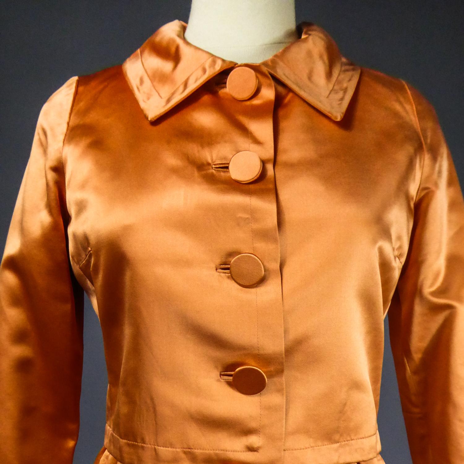 Circa 1950/1960
France

Ensemble veste et robe en satin de soie mandarine brillant de la célèbre maison Jacques HEIM datant de la fin des années 1950. Robe sans manches à large décolleté s'évasant à partir de la taille. Deux poches avec revers