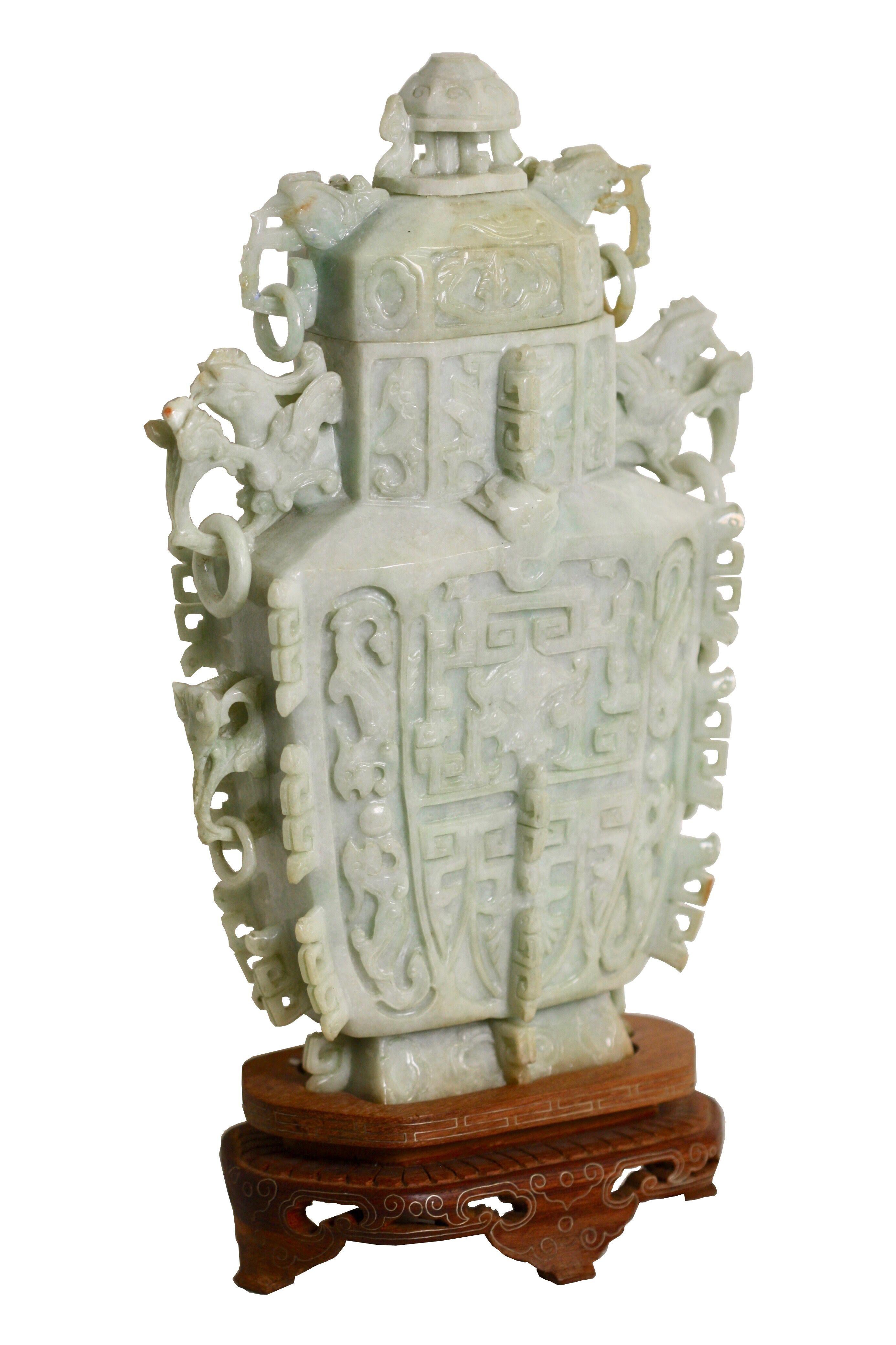 A Jade vase and cover, Chinese
of rectangular section, the waisted neck flanked by a pair of mythical beast handles with loose rings, carved to the front side with mythical masks and kylin, the reverse similarly carved, with thin bands of key-fret