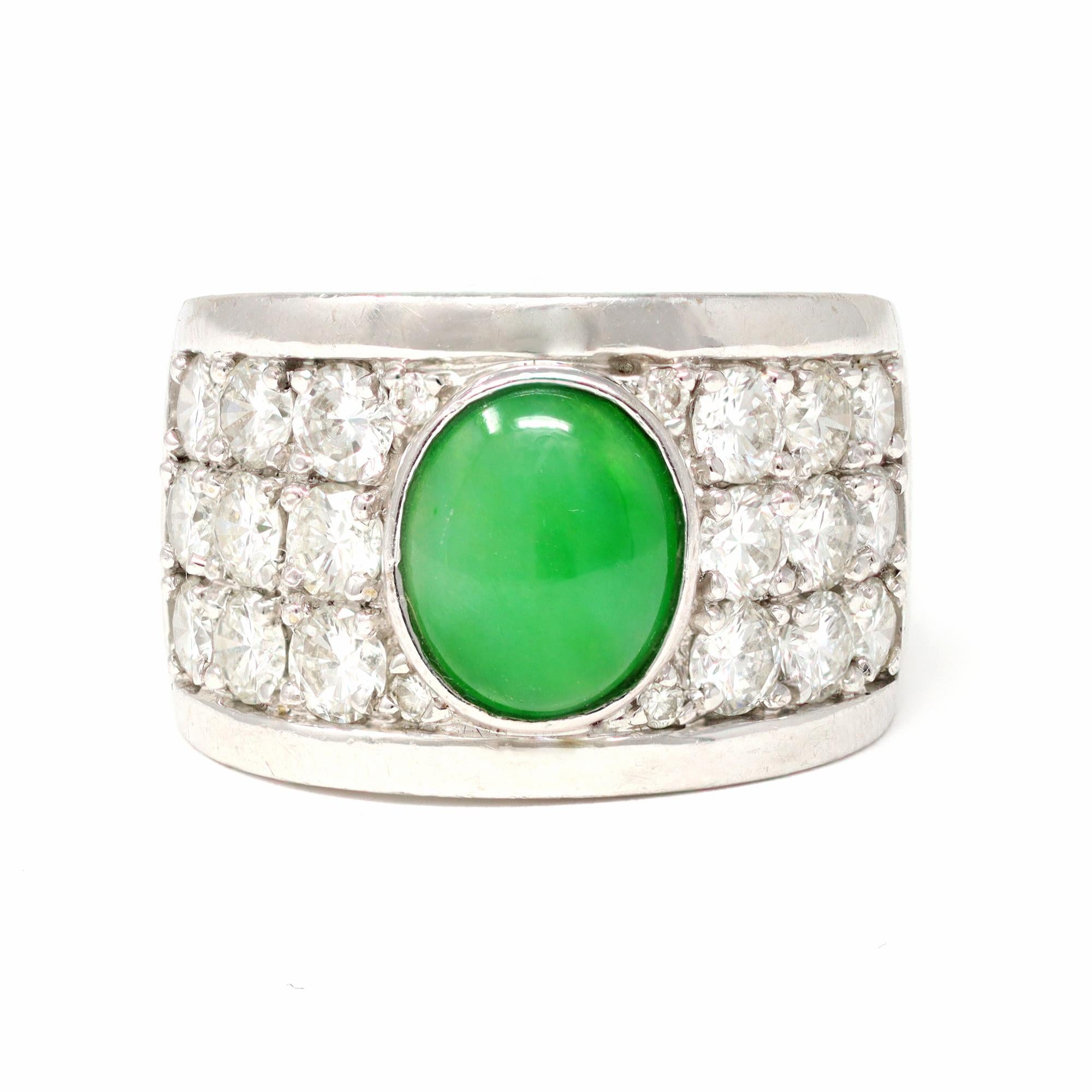 The large band circa 1980 features a natural apple green Jadeite jade cabochon in its center and is surrounded by diamonds set in pavé fashion. The jade cabochon measures 7.5 millimeters wide and 9.2 millimeters long. It is natural with no