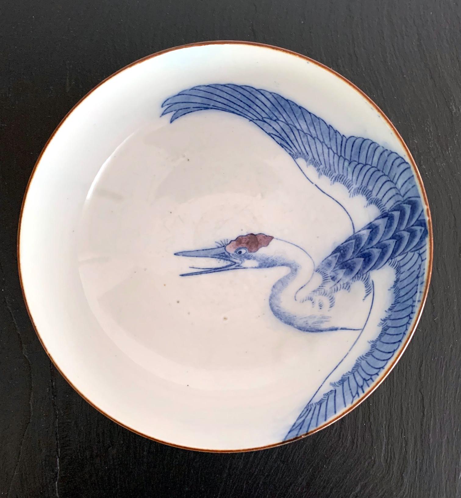 A Kakiemon-style porcelain bowl with an interesting transfer decoration of crane in flight, which spans from the interior to the exterior. Using mostly blue under glaze with a touch of the iron red on the forehead, this delicate piece that shows off