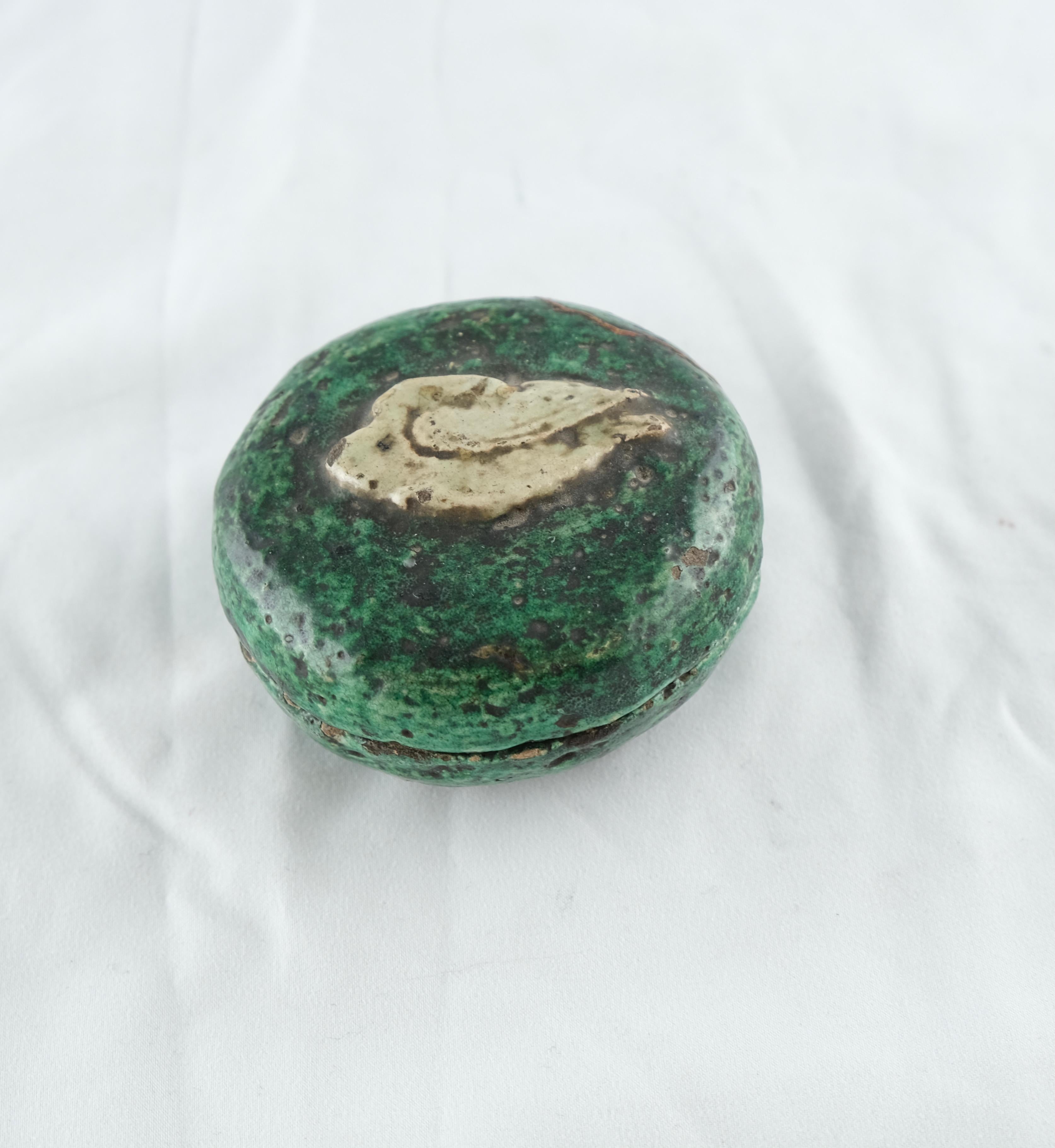 A small box with lid. Earthenware glazes in green and white colours. Mid-19th Century. The lid has a motive of a stylized swan.
The lid with a restoration.