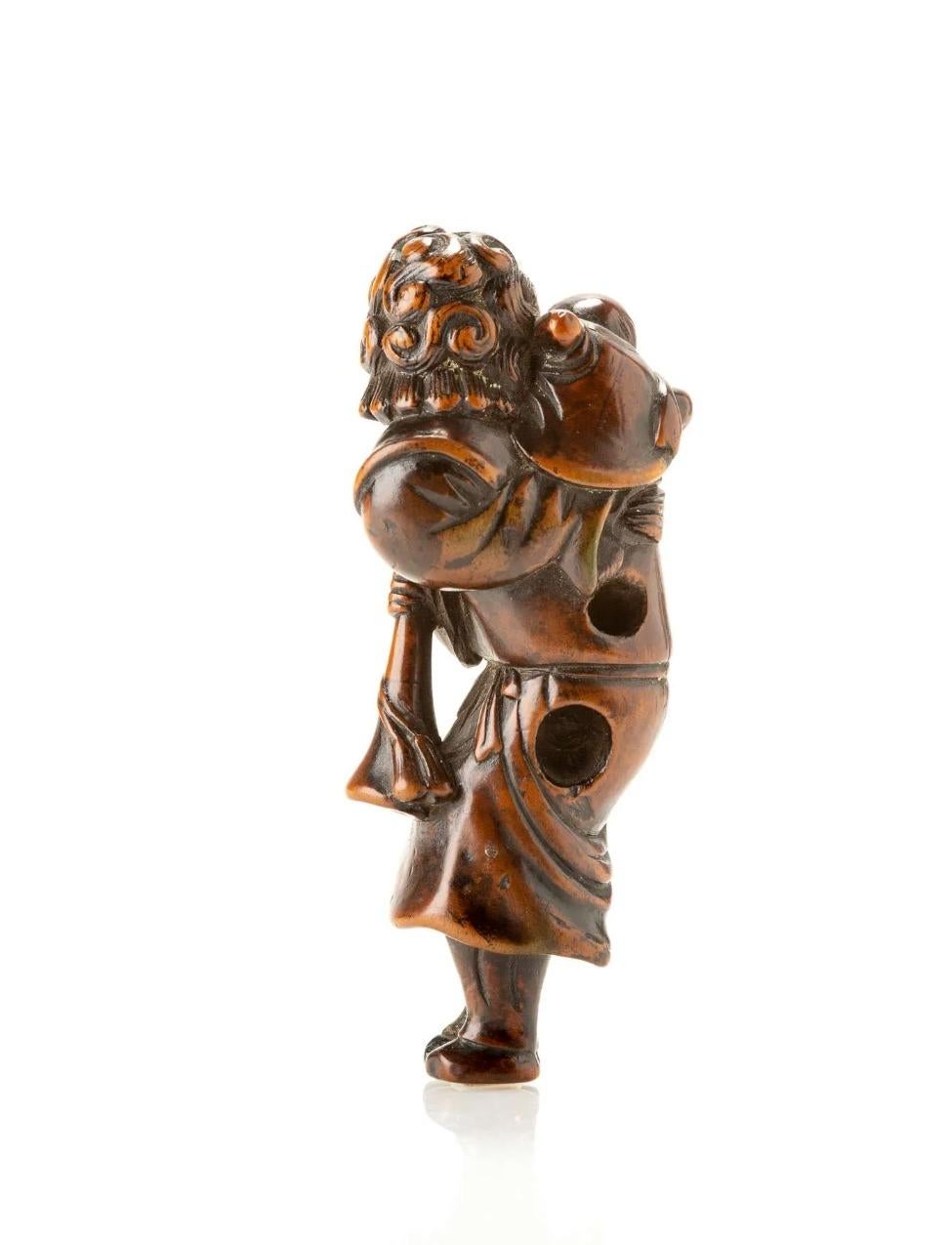Buchsbaum-Netsuke mit der Darstellung eines Holländers mit einem Kind auf der Schulter und einer Trompete.

Ausgezeichnete blonde Patina auf der Vorderseite im Kontrast zu dem dunkleren Teil auf der Rückseite.

Große Himotoshi-Löcher in der