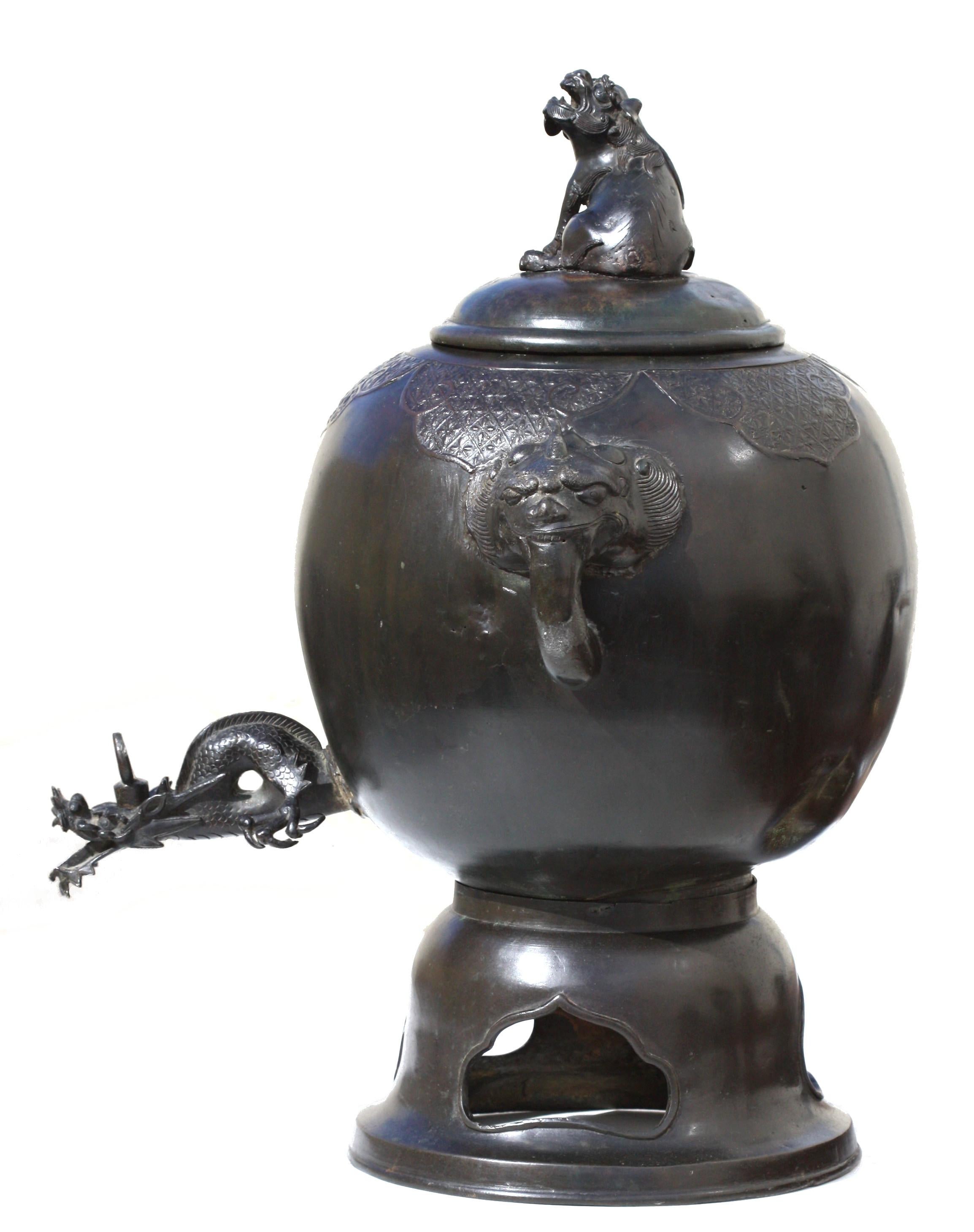 
A Japanese Bronze Ceremonial Samovar with Cover
Meiji period, late 19th century
of round section with wide shoulders tapering towards the tall, splayed foot, the neck with foo-dog handles, supporting a domed cover with a foo-dog finial, 12 x 21 in.