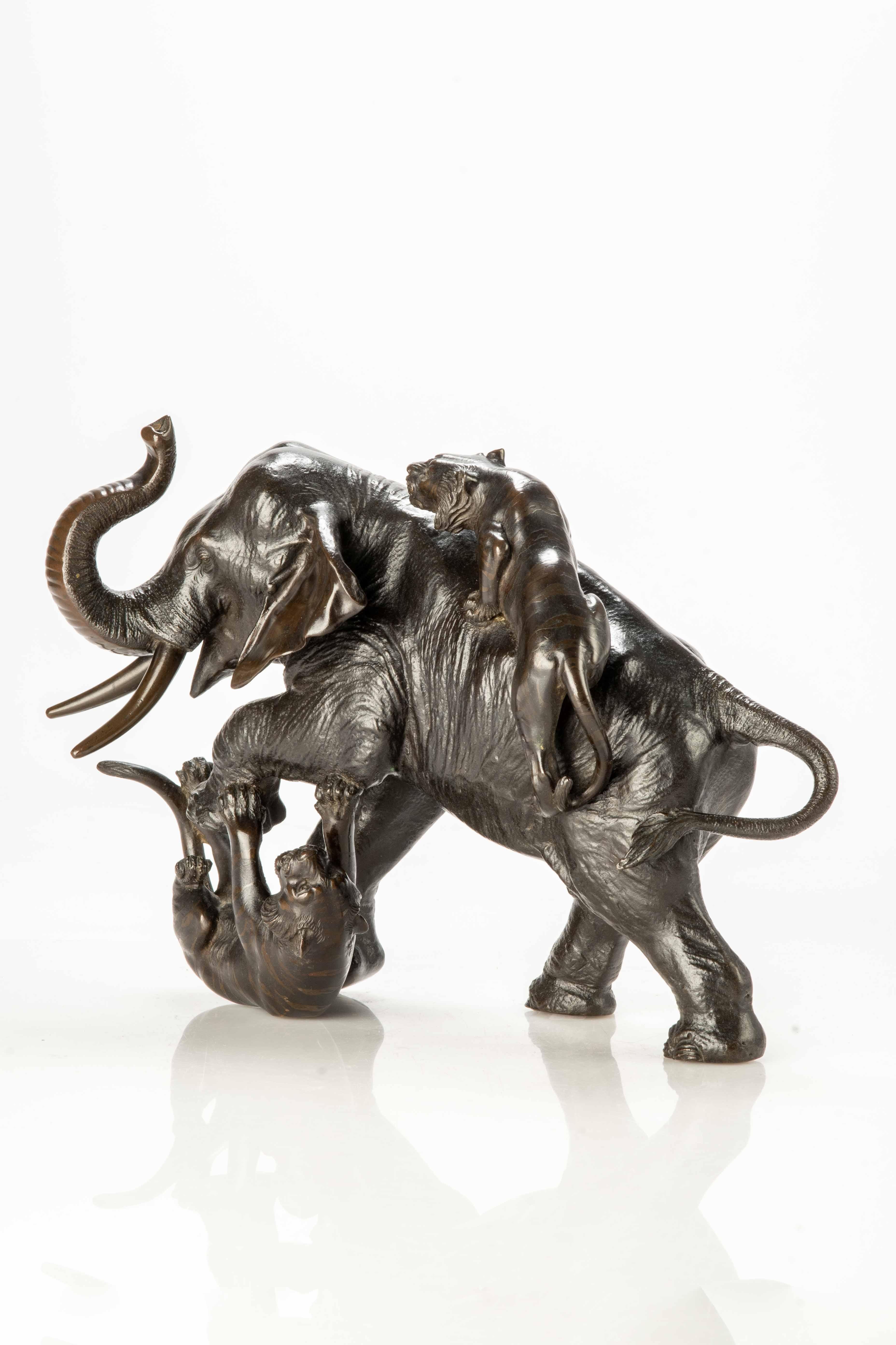Patinated bronze okimono depicting an elephant defending itself from the attack of two tigers: one on its back and the other under its paw.

Very well worked in the details of the elephant's skin, in contrast with that of the two double patina