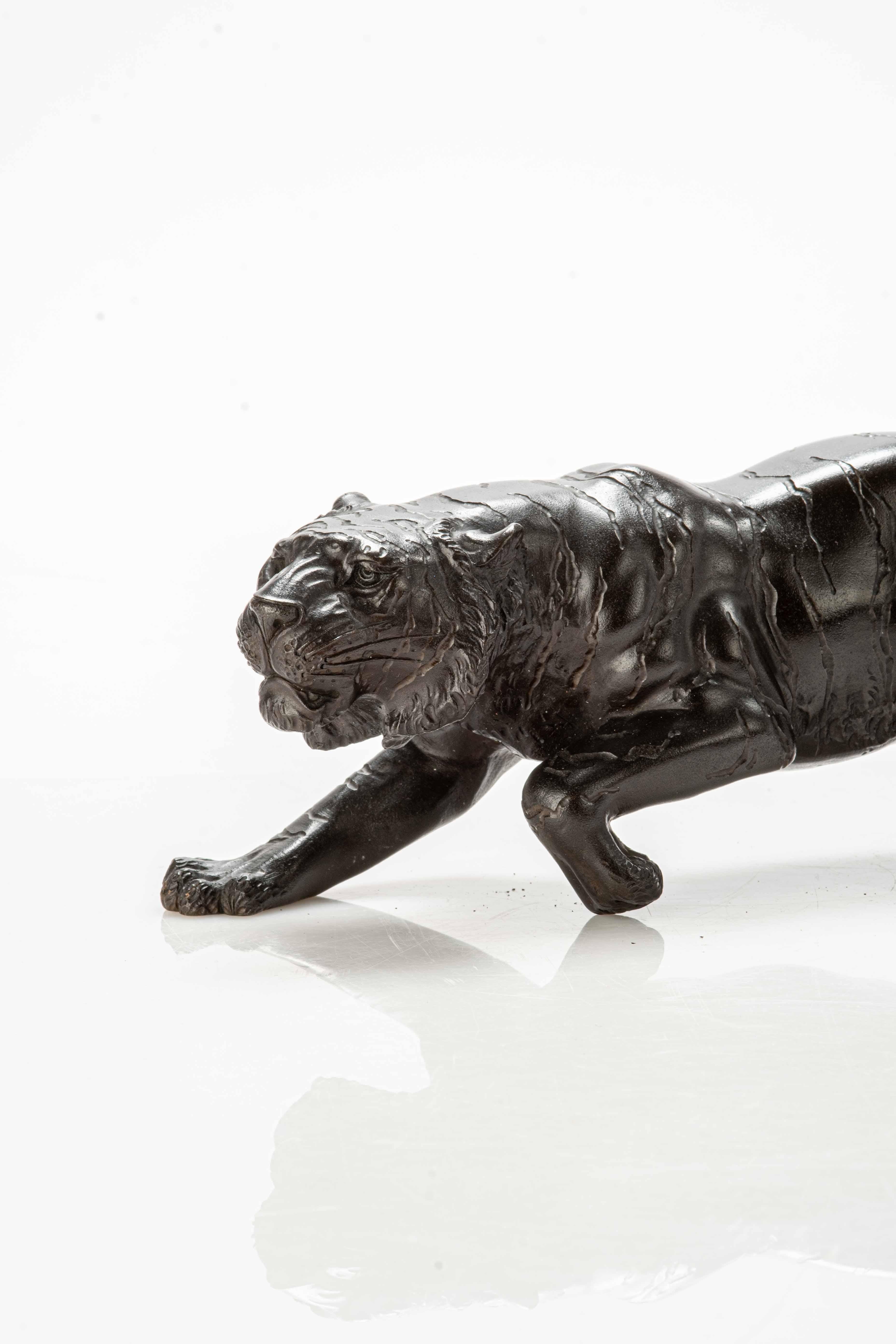 Bronze okimono depicting the study of a powerful tiger in a furtive position.

The animal is represented with its legs bent, its tail curled upwards and its body in a lowered position just before launching the attack.

The streaks of the fur,