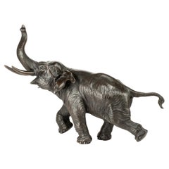 A Japanese bronze sculpture depicting a running elephant with its raised trunk