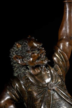 A Japanese bronze sculpture depicting an oni with a ceremonial kōro