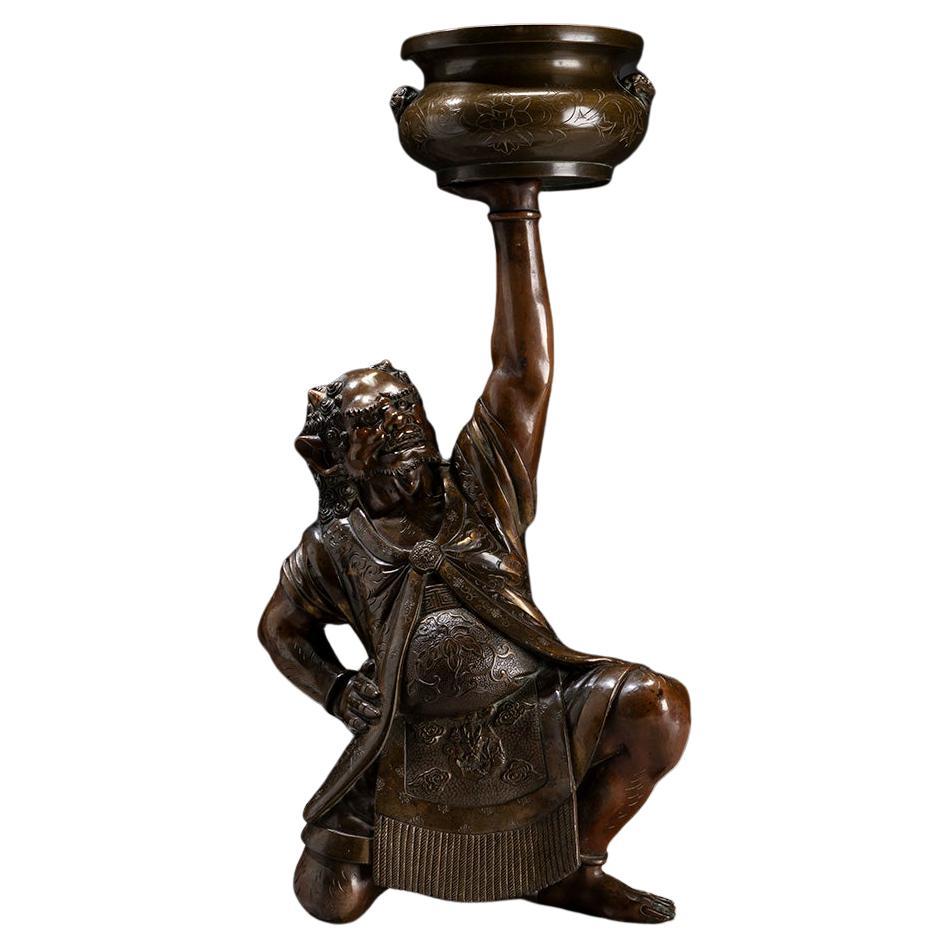 A Japanese bronze sculpture depicting an oni with a ceremonial kōro