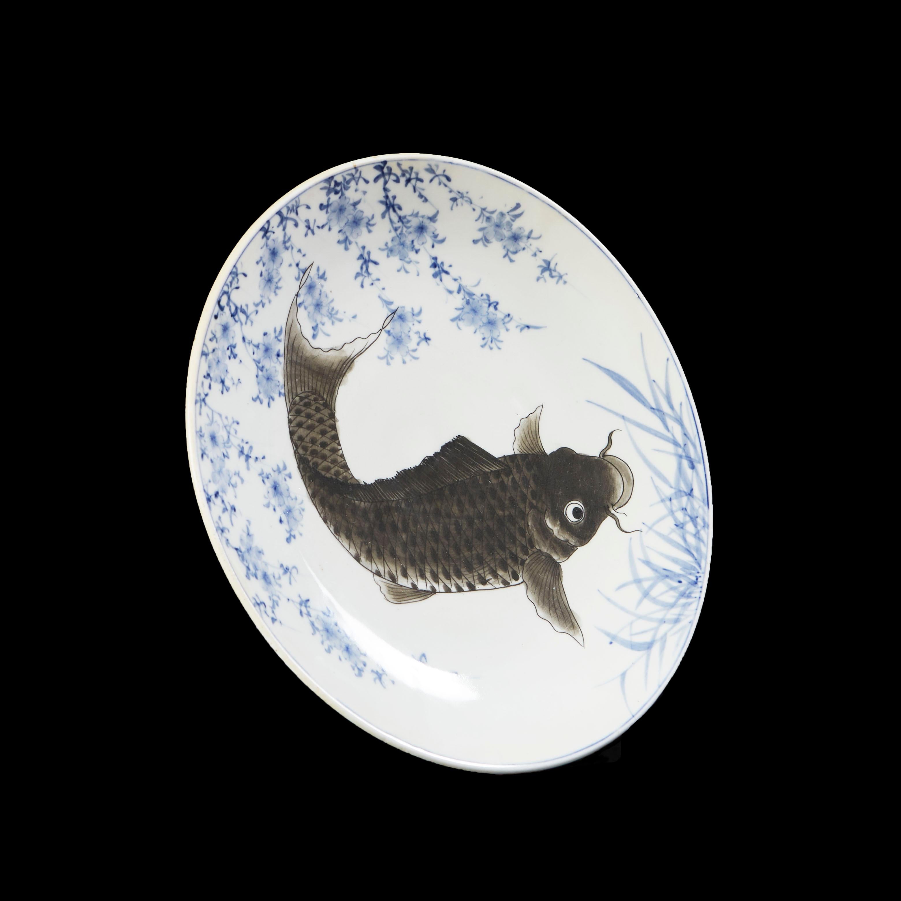 A fine late nineteenth century Japanese charger, with swimming decorative carp with whiskers and painted scales, swimming amongst blue reeds on a white ground.