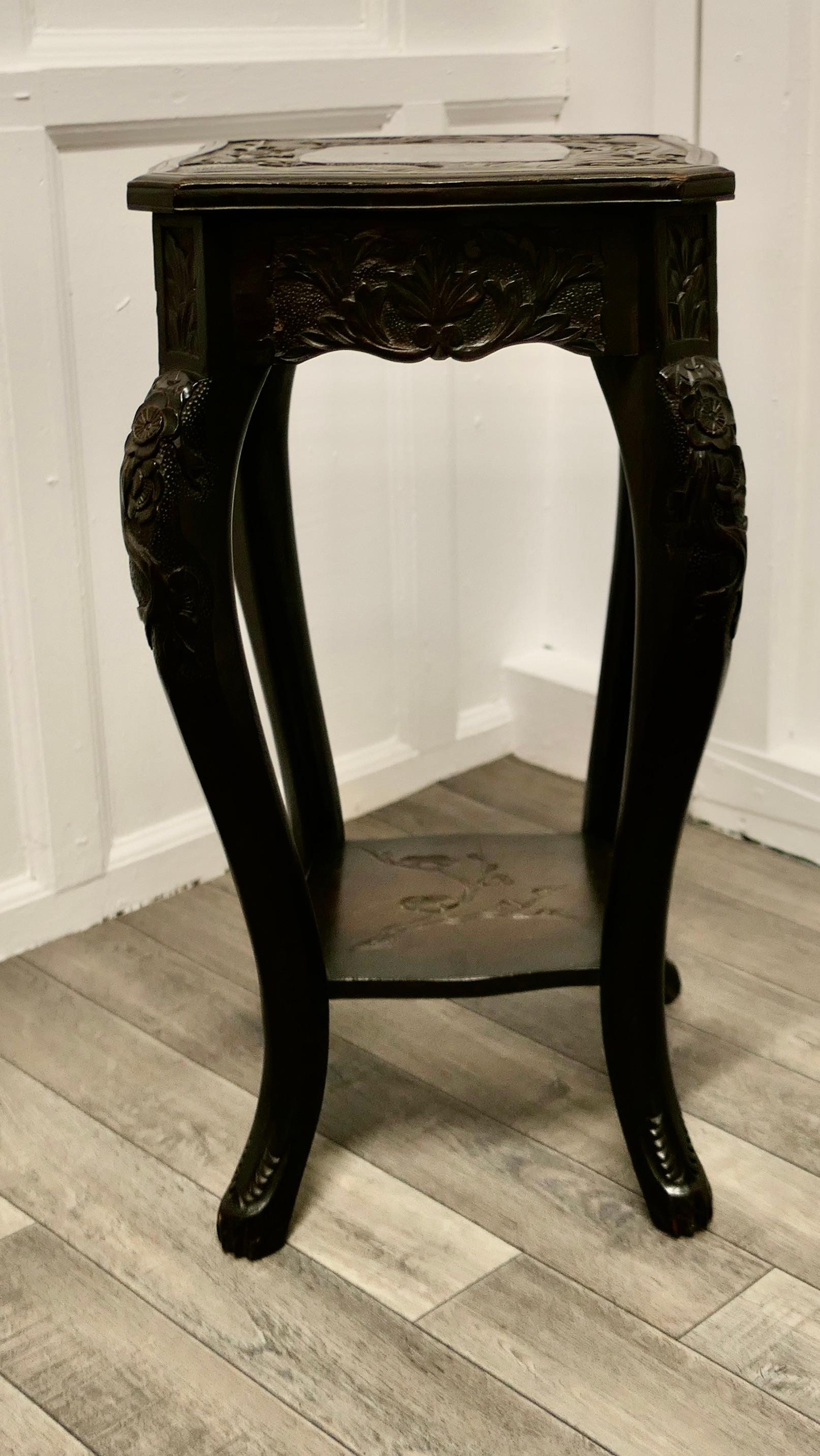 A Japanese carved lamp table

The square top has a plain centre panel the border is beautifully carved with leaves and it is set on bowed deeply carved cabriole style legs.
The table has an under tier shelf which is also carved, this in a more