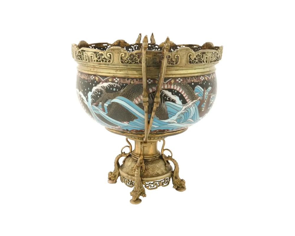 An antique Japanese gilt bronze centerpiece urn or jardiniere with enameled body. Late Meiji period, before 1912. The foot is decorated with sculptural sea creatures. The item has figurative double handles and ornamental rims. The cloisonne enamel