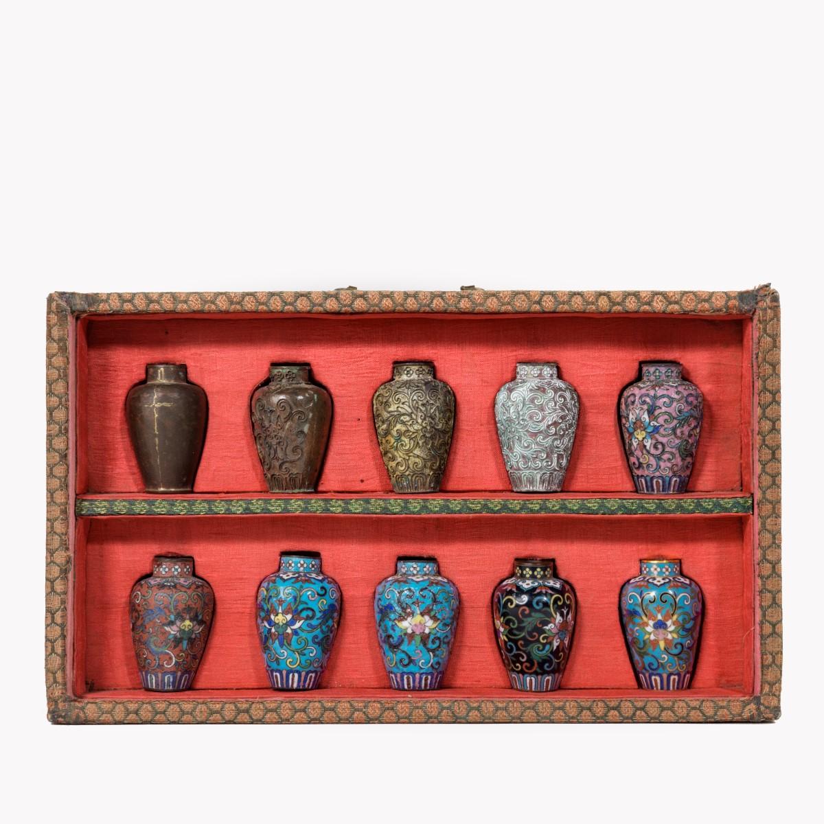 A Japanese cloisonné sample set, comprising 10 small metal vases showing the various stages of cloisonné production, all in a silk brocade covered box with a red silk lining. Meiji period, circa 1900.
Measures: Box 11 1/4 in. 6 3/4in
Single vase