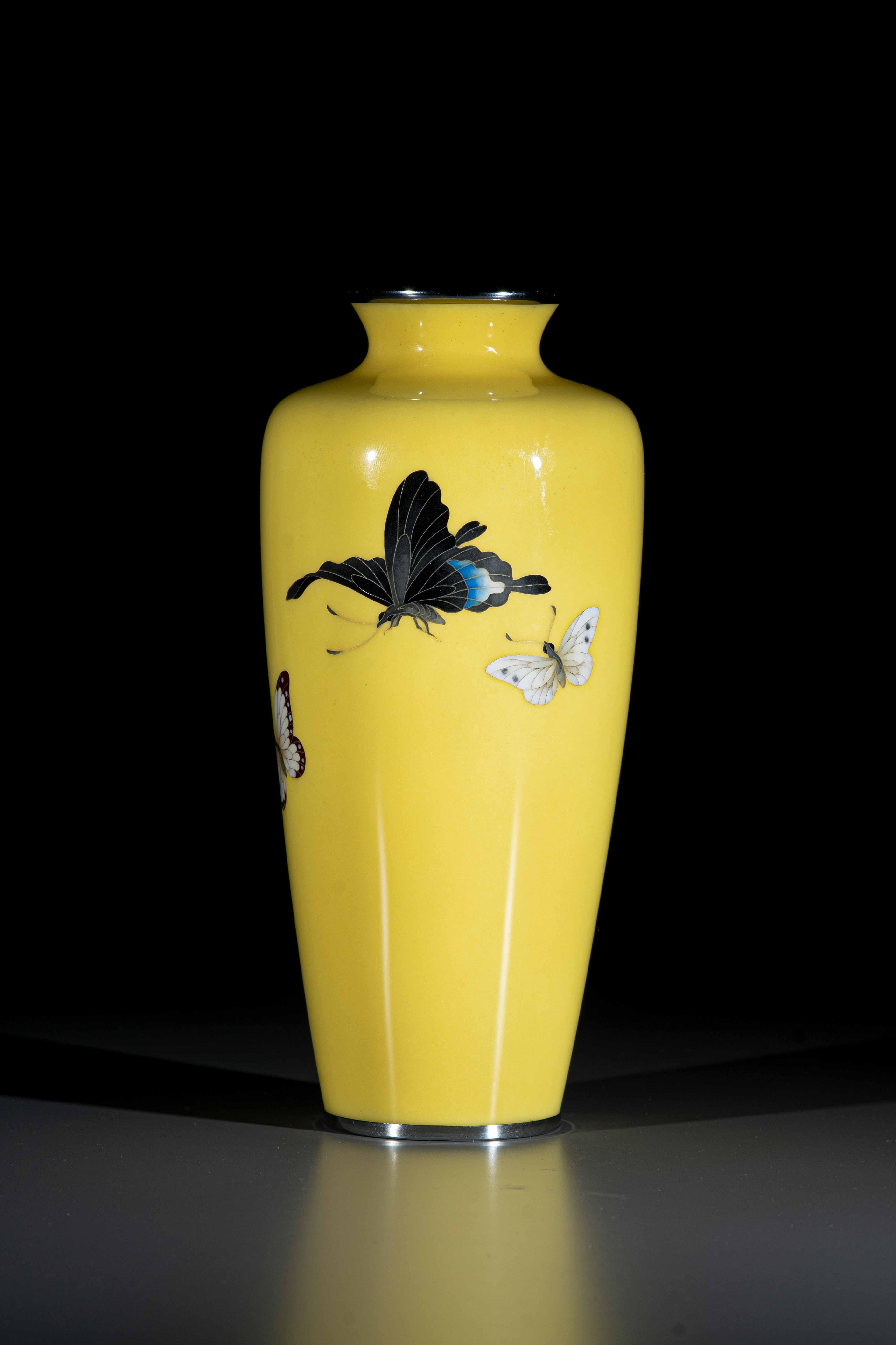 Jarrón de metal y esmalte cloisonné con fondo monocromo amarillo, decorado con tres mariposas voladoras con la marca de la empresa Ando.

Periodo: Taisho 1920 ca.

Dimensiones: 21 x 10 cm.

Estado de conservación: Excelente estado