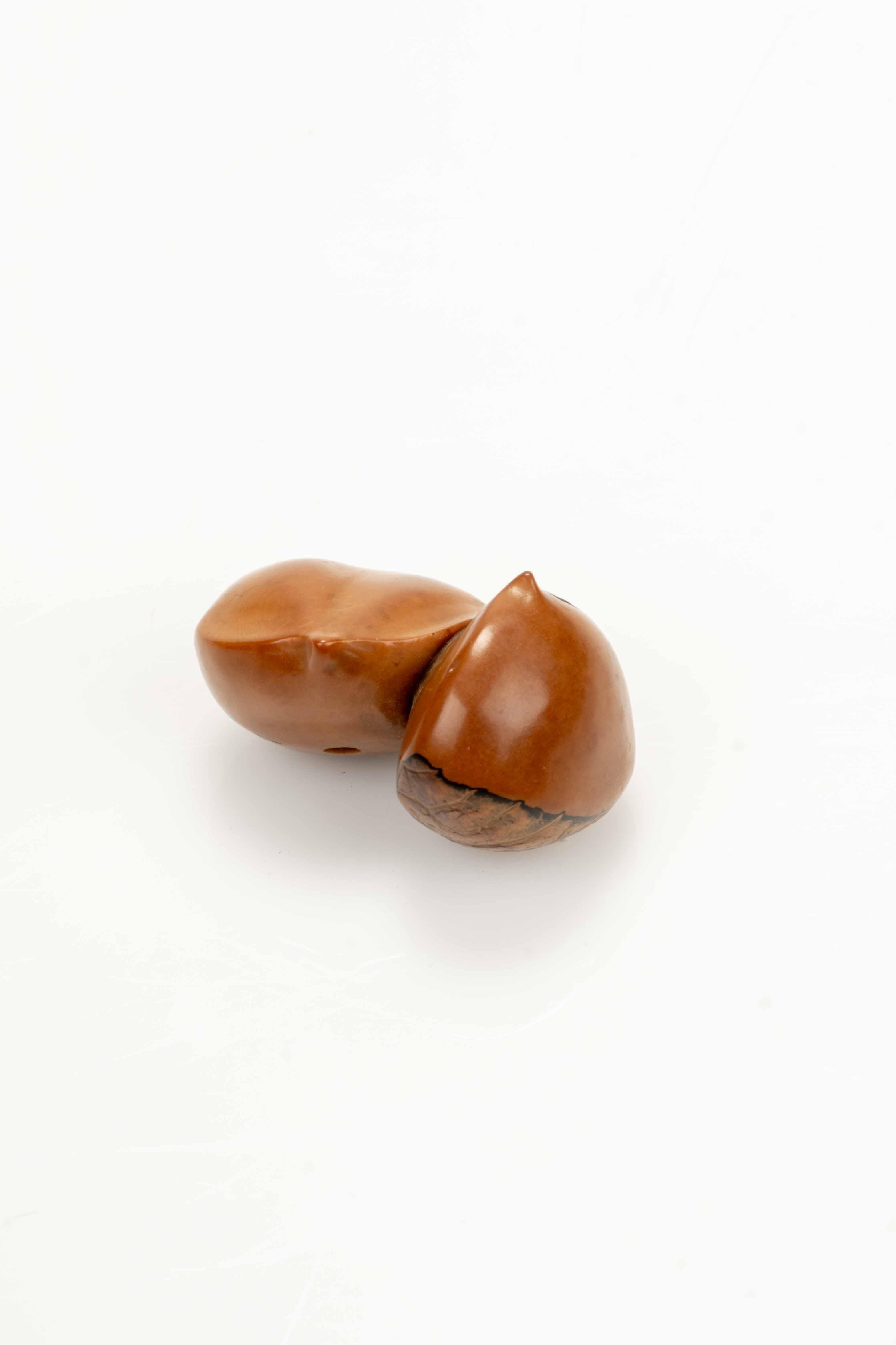 A Japanese netsuke carved from corozo nut, depicting a pair of finely detailed chestnuts. The signature “Ikko” is engraved next to the himotoshi. 

Period: Meiji, late 19th century 
Dimensions: 2.7 × 4.6 × 3.5 cm 
Condition: Excellent condition
