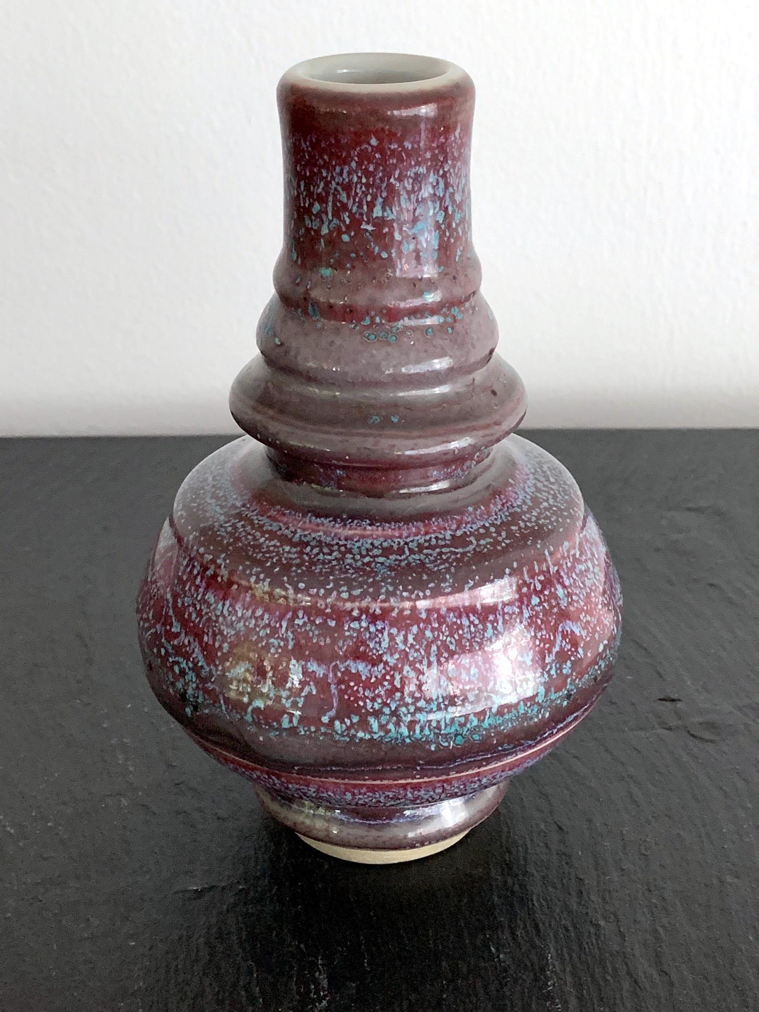 A garlic bottle vase in an archaic Chinese form, but likely Japanese in origin. Several circumventing grooves however, suggest a more modern age. It was done in a brilliant purple glaze over a robin egg blue background glaze. The bubbling and