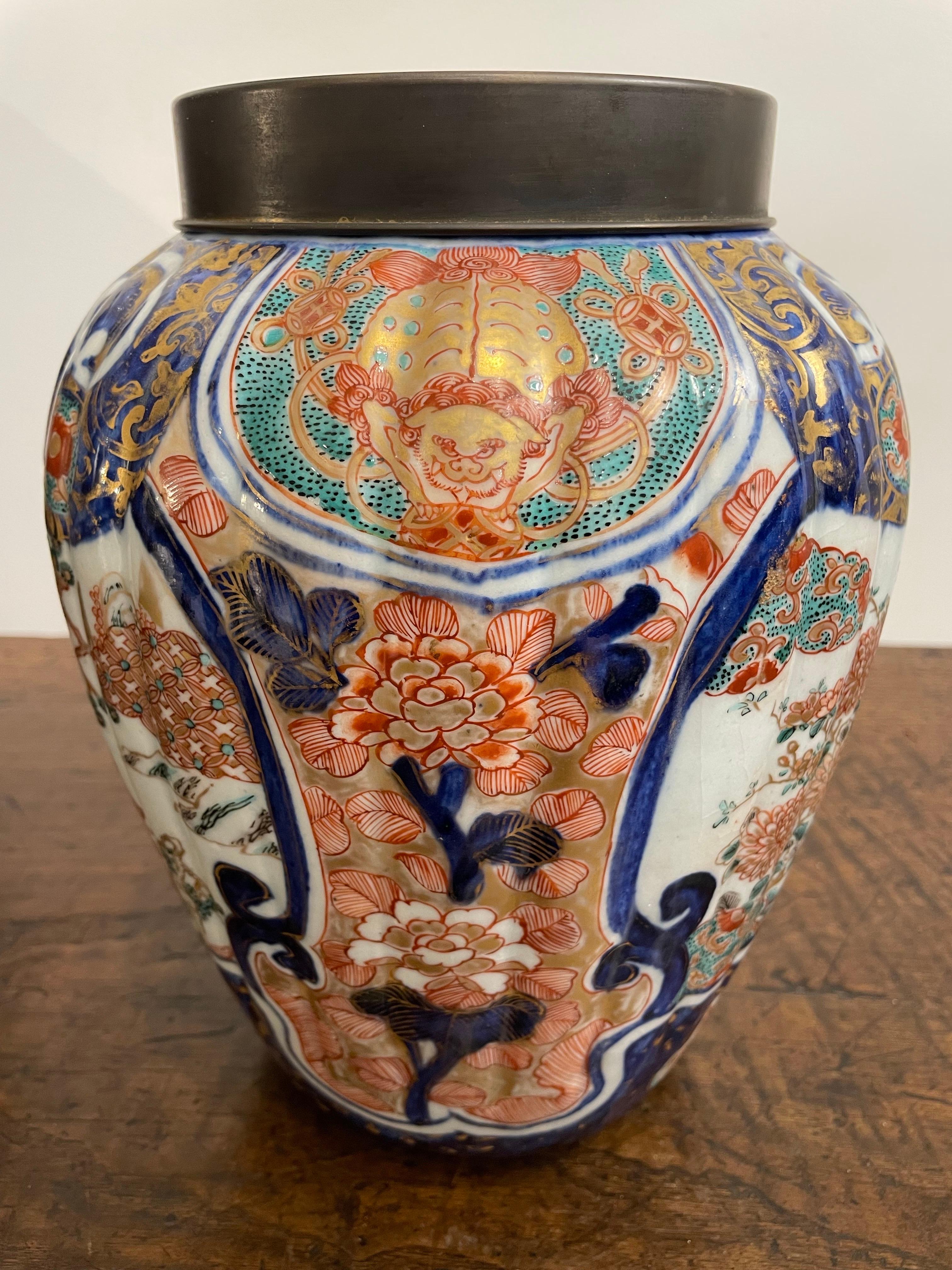 A Japanese Fluted Imari Vase with Mark and Metal Cover, 19th Century

Provenance:  
Private Melbourne Collection.

Description:
The fluted Imari vase with a short everted collar surrounded by a band of cobalt and gilt foliate panels divided by red