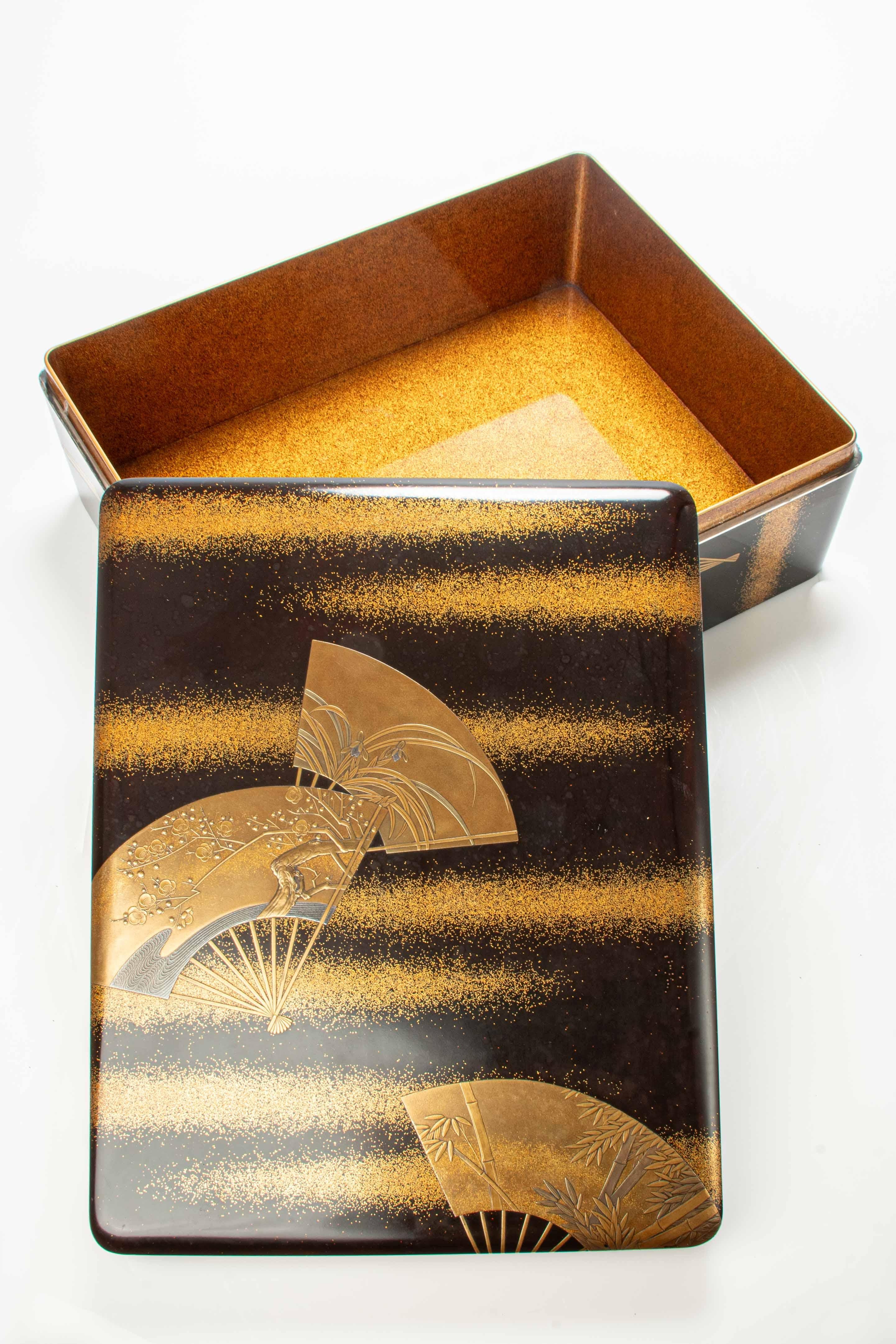Lacquer box decorated with gold and silver details using the traditional Japanese technique of takamaki-e and hiramaki-e depicting a motif of three superimposed fans on a nashiji lacquer background.

Each fan is decorated with different flowers,