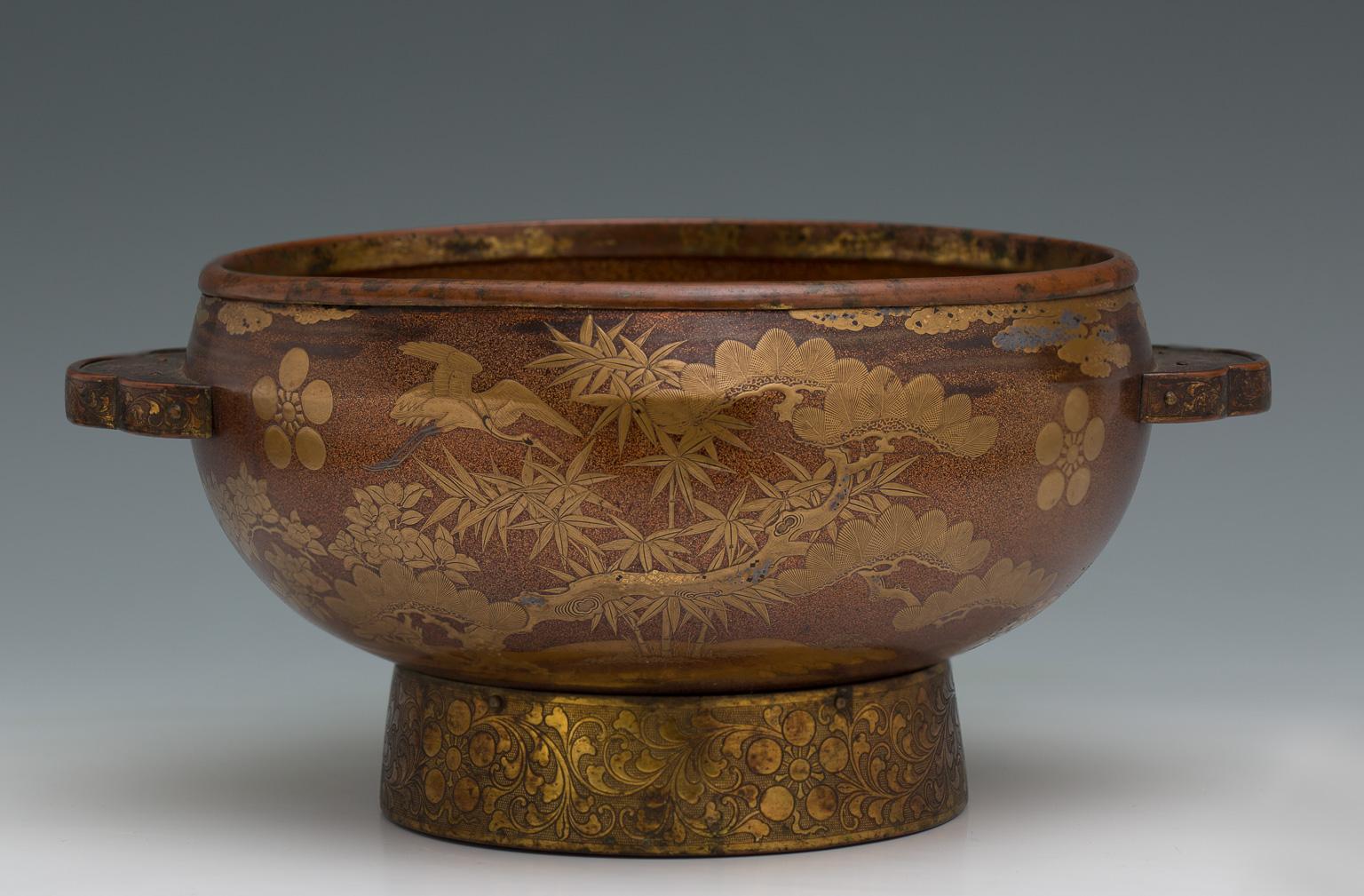 Wooden basin with ear-shaped handles decorated with hiramaki-e lacquer and gold and silver kirigane on a nashi-ji ground.
The large and thick antique wooden basin is completely lacquered in nashiji gold, with cranes flying among pines, bamboo and