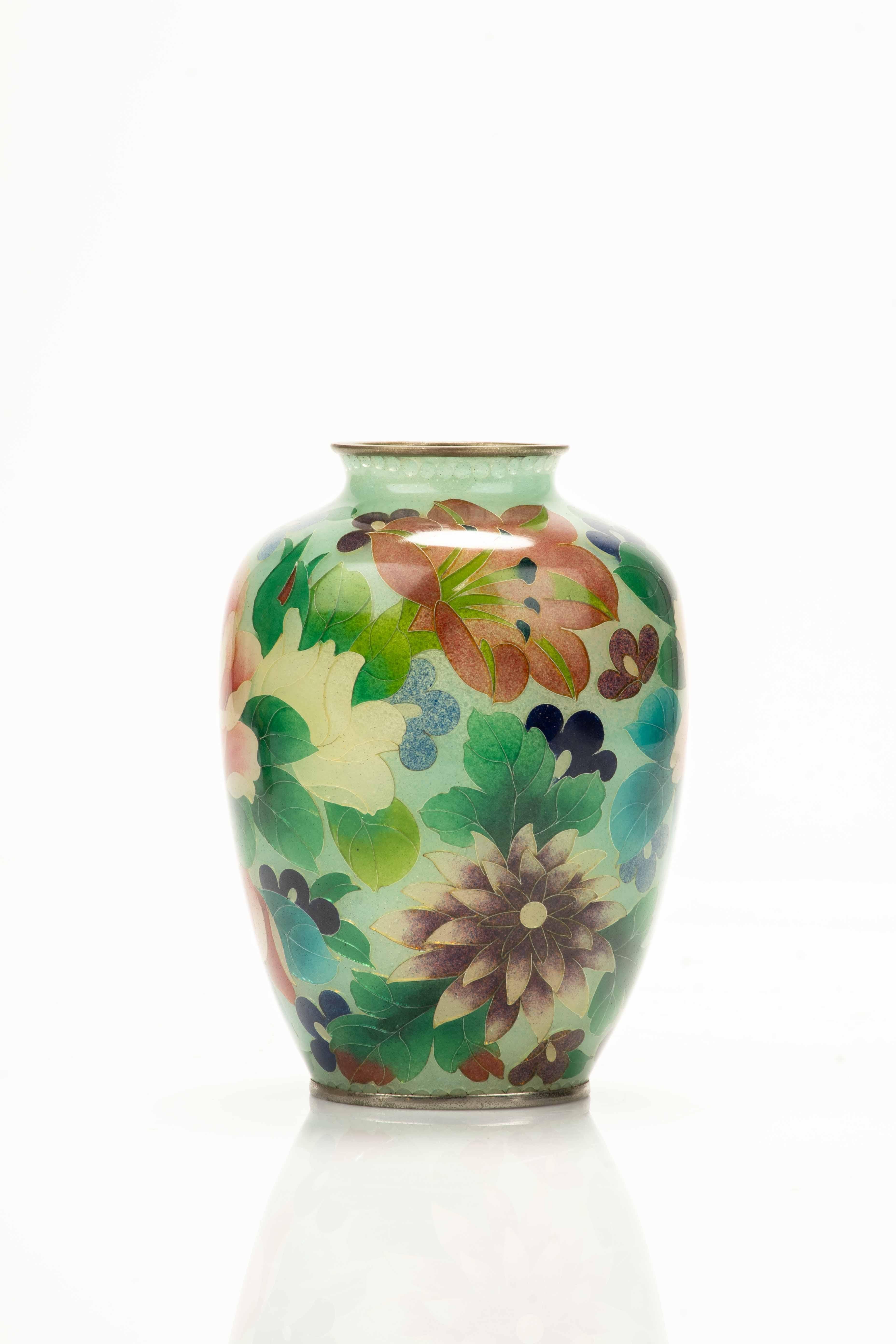 A Japanese plique-à-jour vase crafted in translucent glass and embellished with polychrome enamels applied within delicate silver-wire cells.

Each side displays a different arrangement of flowers, forming a rich and harmonious floral composition