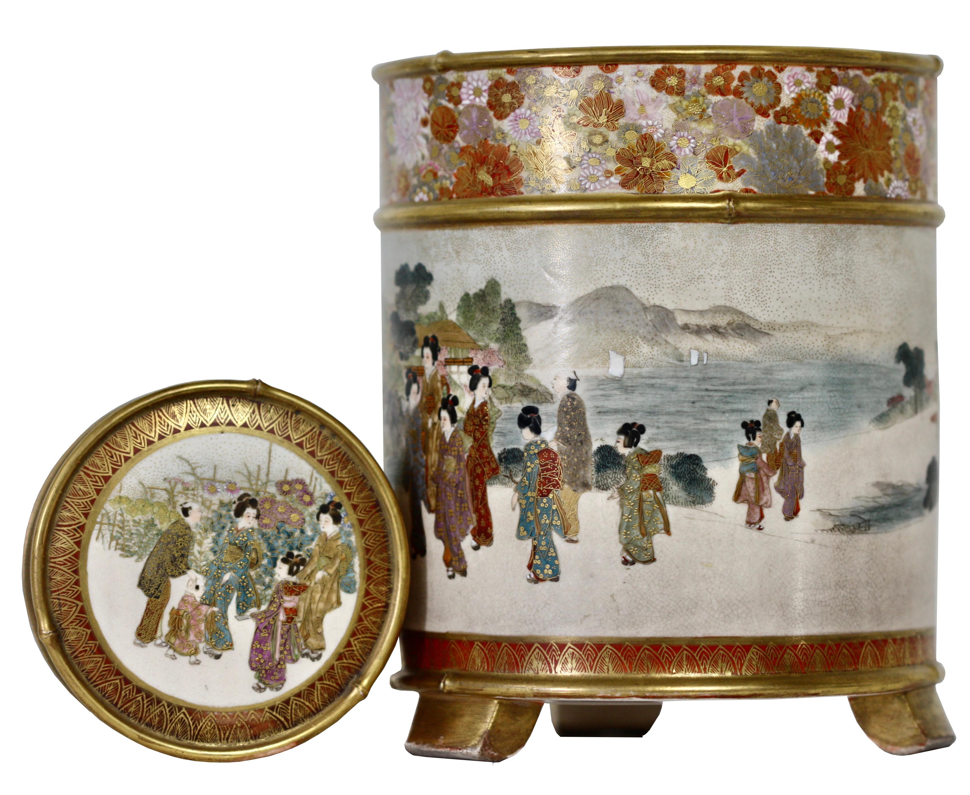 A Japanese Satsuma cylindrical koro and cover, signed Gyokuzan,
Meiji period (1868-1912)
Raised on three supports, painted and gilt with a continuous scene of ladies and children parading at leisure before a river scene, below a band of a