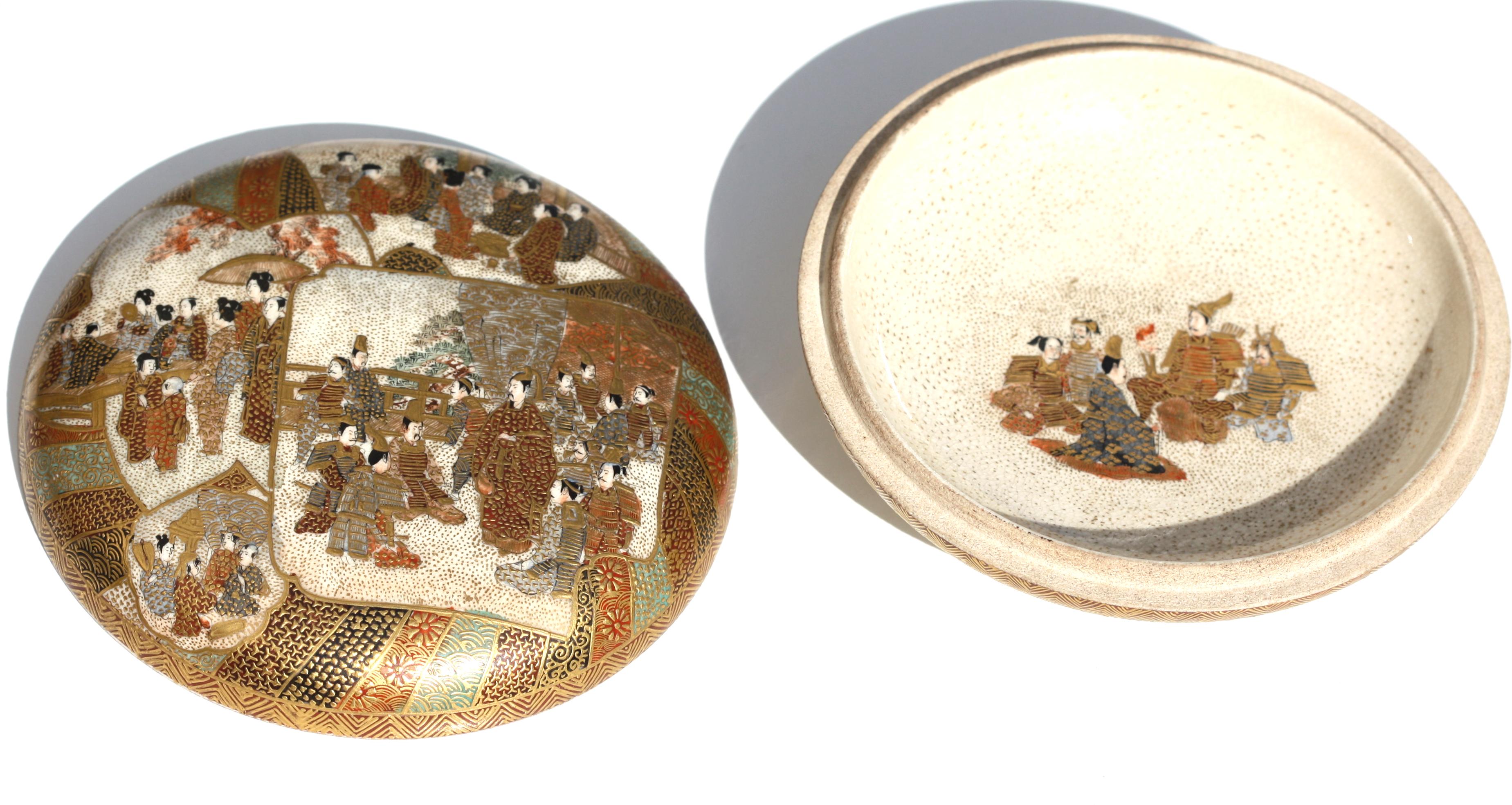 
A Japanese Satsuma earthenware circular box and cover, MEIJI PERIOD (1868-1912), the interior and exterior decorated with gilt and contrasting figural scenes, signed Satsuma yaki sei with the Satsuma mon
Diameter 10.7 cm, 4.25 in.