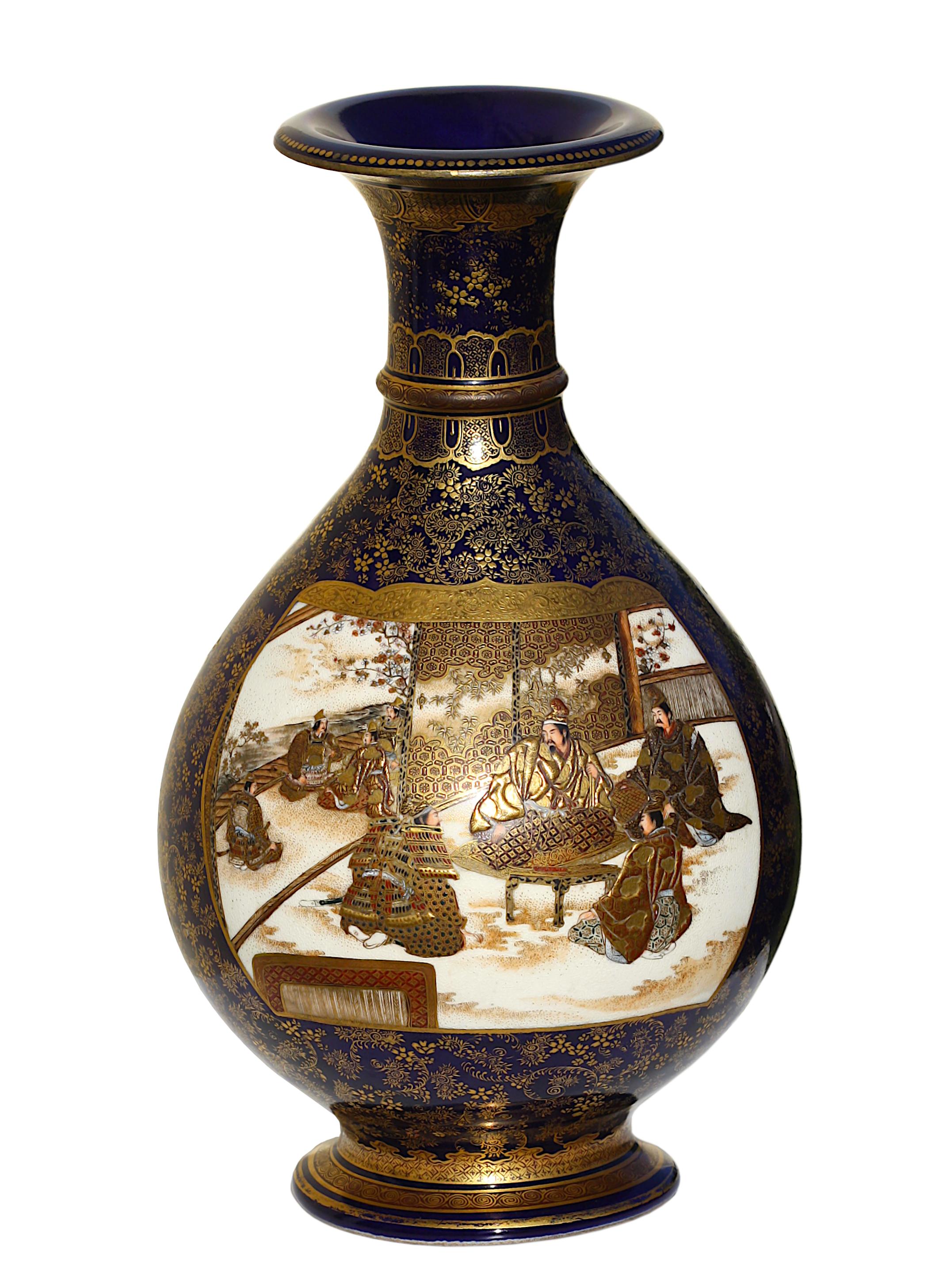A Japanese Satsuma Earthenware Vase by Kinkozan, Meiji period (1868-1912)
The body inset with two panels, one depicting figures seated around a table, the other painted with a joyful scene in a shrine, all reserved on a blue ground decorated with a