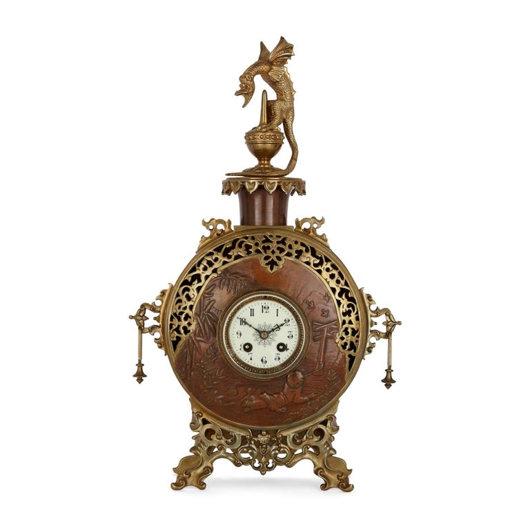 A Japonisme gilt-bronze and brass three-piece clock set
French, Late 19th Century
Clock: height 52cm, width 31cm, depth 12cm
Candelabra: height 55cm, width 32cm, depth 9cm

Made in France in the late nineteenth century in the popular Japonisme