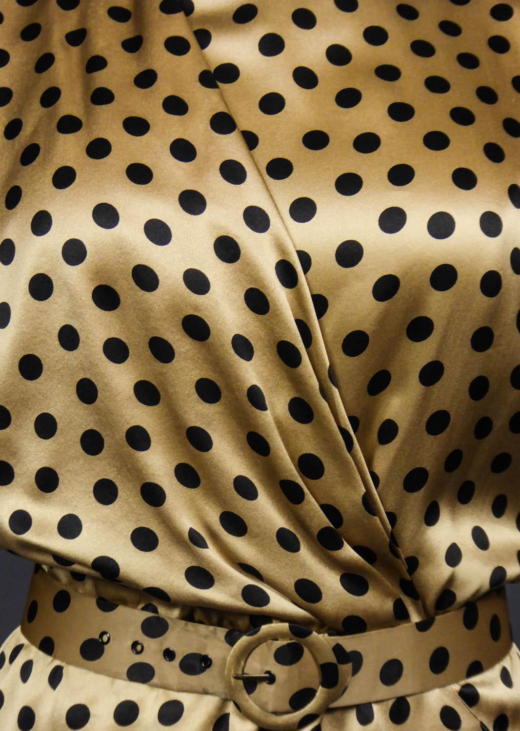 Circa 1985
France
Jean-Louis Scherrer blouse or top in champagne silk satin with black dots. Long sleeves with zip at the wrists and epaulettes. Crew neck collar with shawl draped effect and crossed from the shoulder. Size tightened by an elastic