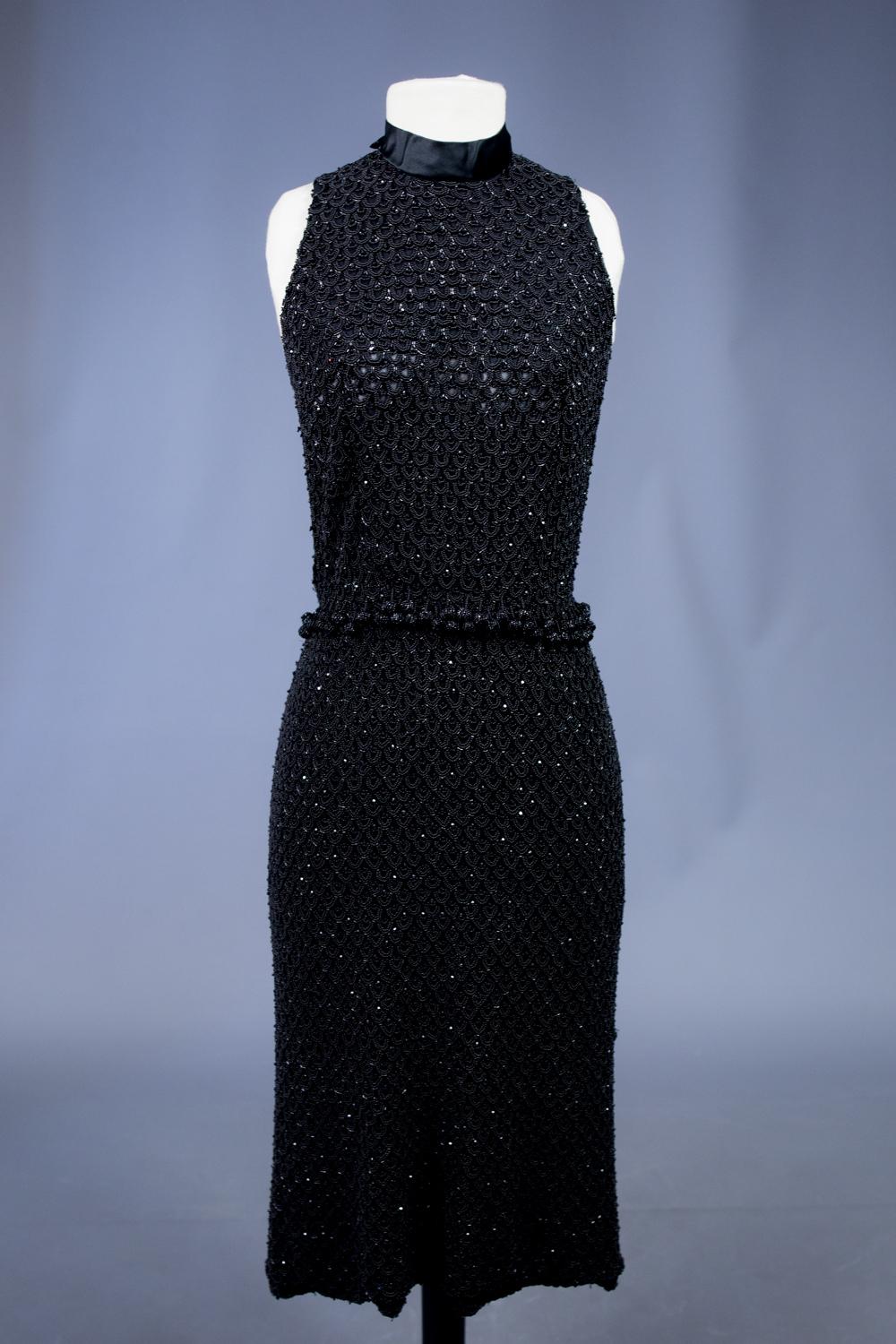 Circa 1960/1965

France

Elegant cocktail dress entirely embroidered with black jet beads probably Haute Couture, inspired by Chinese qipao and dating from the 1960s. Sheath dress, low-cut shoulders and Mao collar in black satin adorned with a