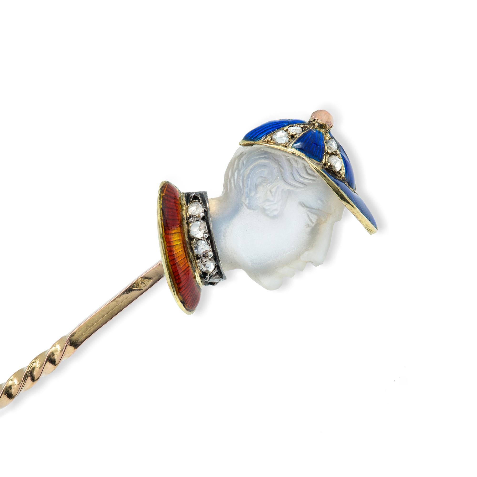 A jockey moonstone cameo stick-pin, the realistically carved moonstone in the form a jockey's head, with a blue enameled and rose-cut diamond-set cap, to a rose-cut diamond-set and red- enameled collar, all mount in yellow gold, with yellow gold pin