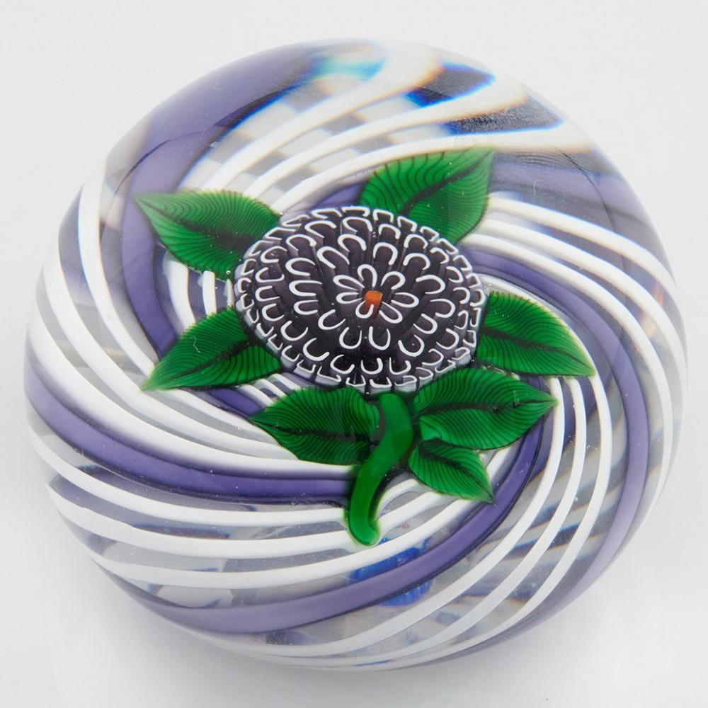 Heading : A John Deacons Pompom Lampwork Paperweight 2014
Date : 2014
Origin : Scotland
Features : A large millefiori black flower with lampworl leaves and stem on a purple and white swirl ground
Marks : A JD2014 signature cane to the base
Type :