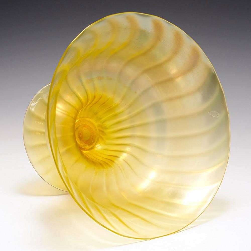 Heading : A John Walsh Walsh iridescent ribbed amber bowl
Date : c1935
Origin : John Walsh Walsh, Birmingham
Bowl Features : An amber ribbed pedestal bowl in iridised amber
Marks : None
Type : Lead free
Size : diameter 22cm, height