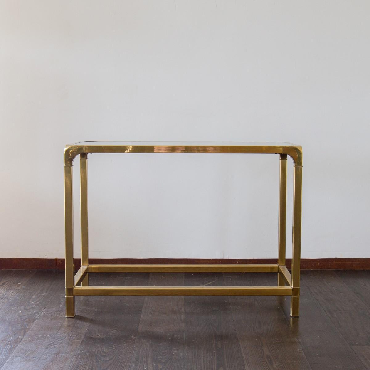 A brushed brass framed, two tiered console table with inset glass tops and curved corner details designed by John Widdicomb, 1970s.

 