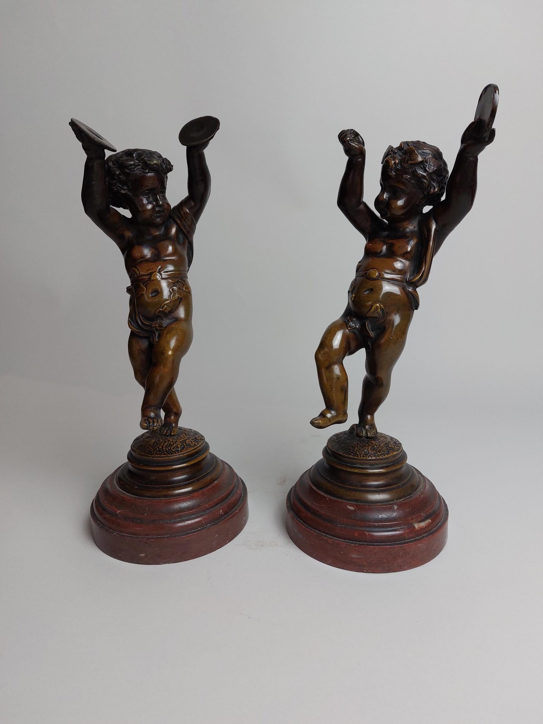 A joyful pair of 19th century bronze cherubs (putti) dancing and playing cymbals and a tambourine, on marble bases.