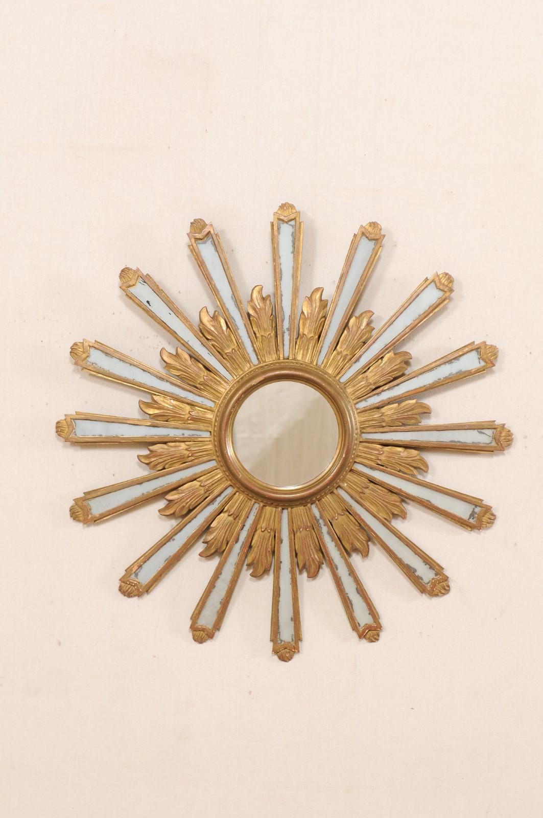 A Spanish sunburst mirror from the early 20th century. This antique mirror from Spain, just shy of 3 feet in diameter, features a circular-shaped frame with central mirror, and gilded sun-rays emerging like a halo radiating out in undulating