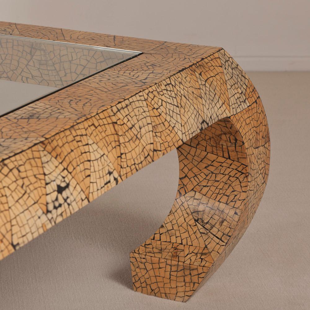 An impressive coconut shell veneered coffee table with the veneers laid in triangular shapes and set upon curved legs and complete with inset glass top, in the style of Karl Springer, 1970s-1980s

Karl Springer established a tiny workshop in