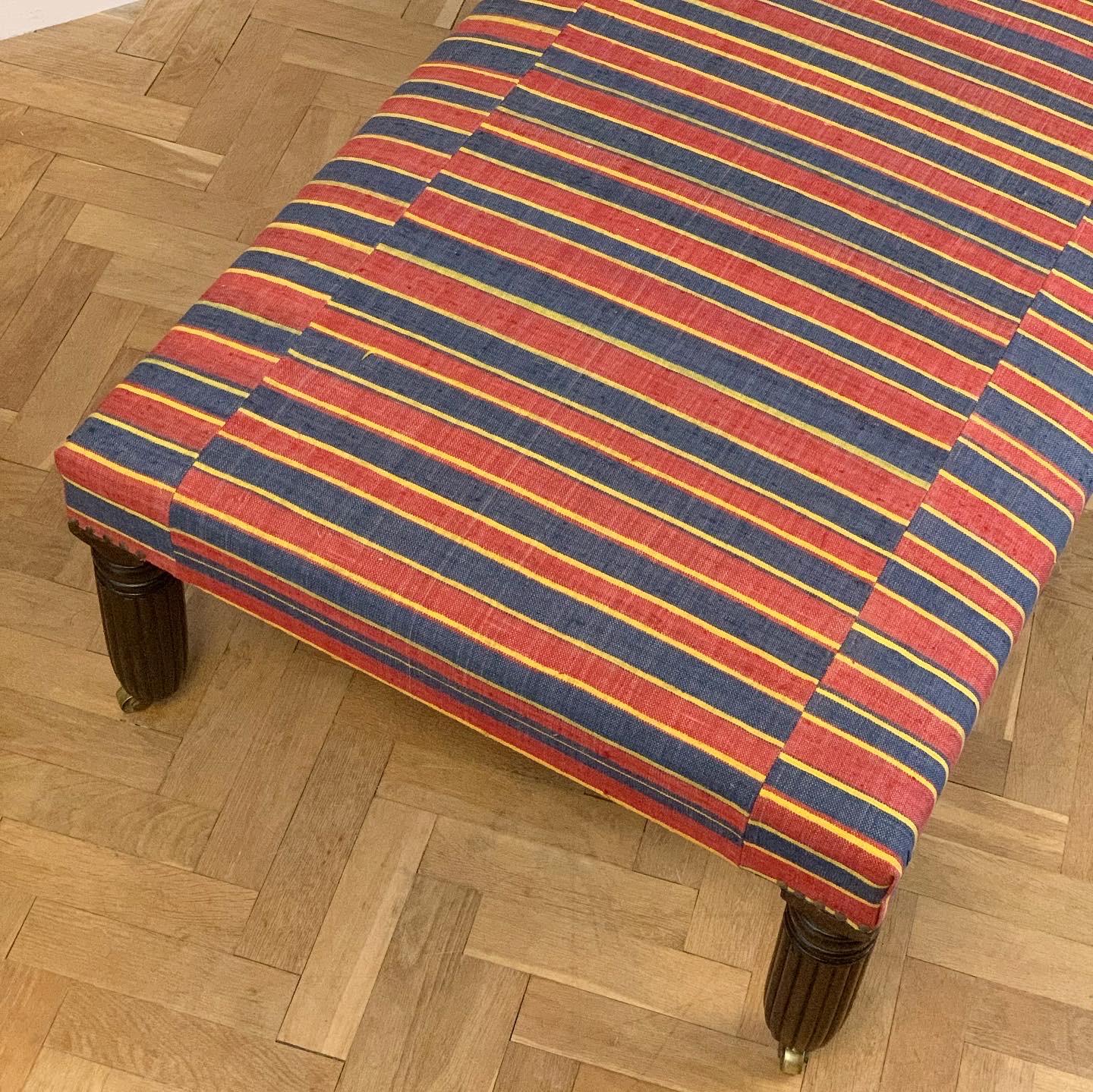 An upholstered stool with mid nineteenth century mahogany reeded and tapered legs covered in a vibrant tri-coloured striped Turkish Kilim.