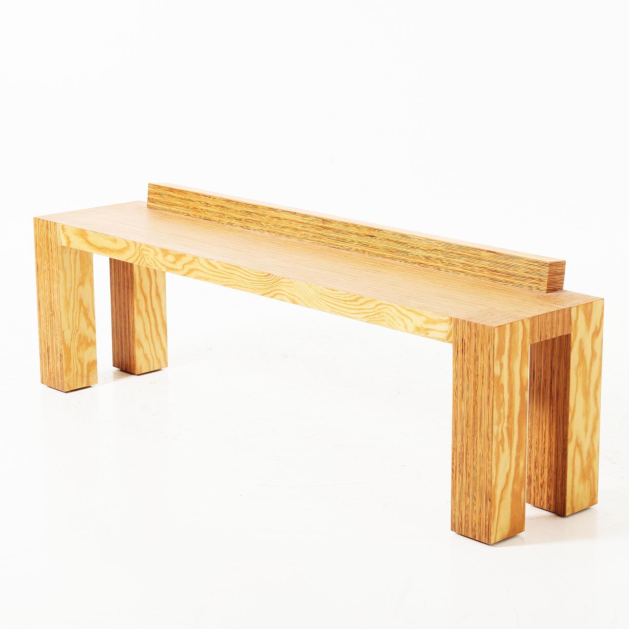 Banc de la fin du XXe siècle fabriqué en pin stratifié, présentant une silhouette minimaliste aux lignes épurées et architecturales. La banquette se caractérise par une assise rectangulaire et un dossier linéaire surélevé, le tout construit dans un