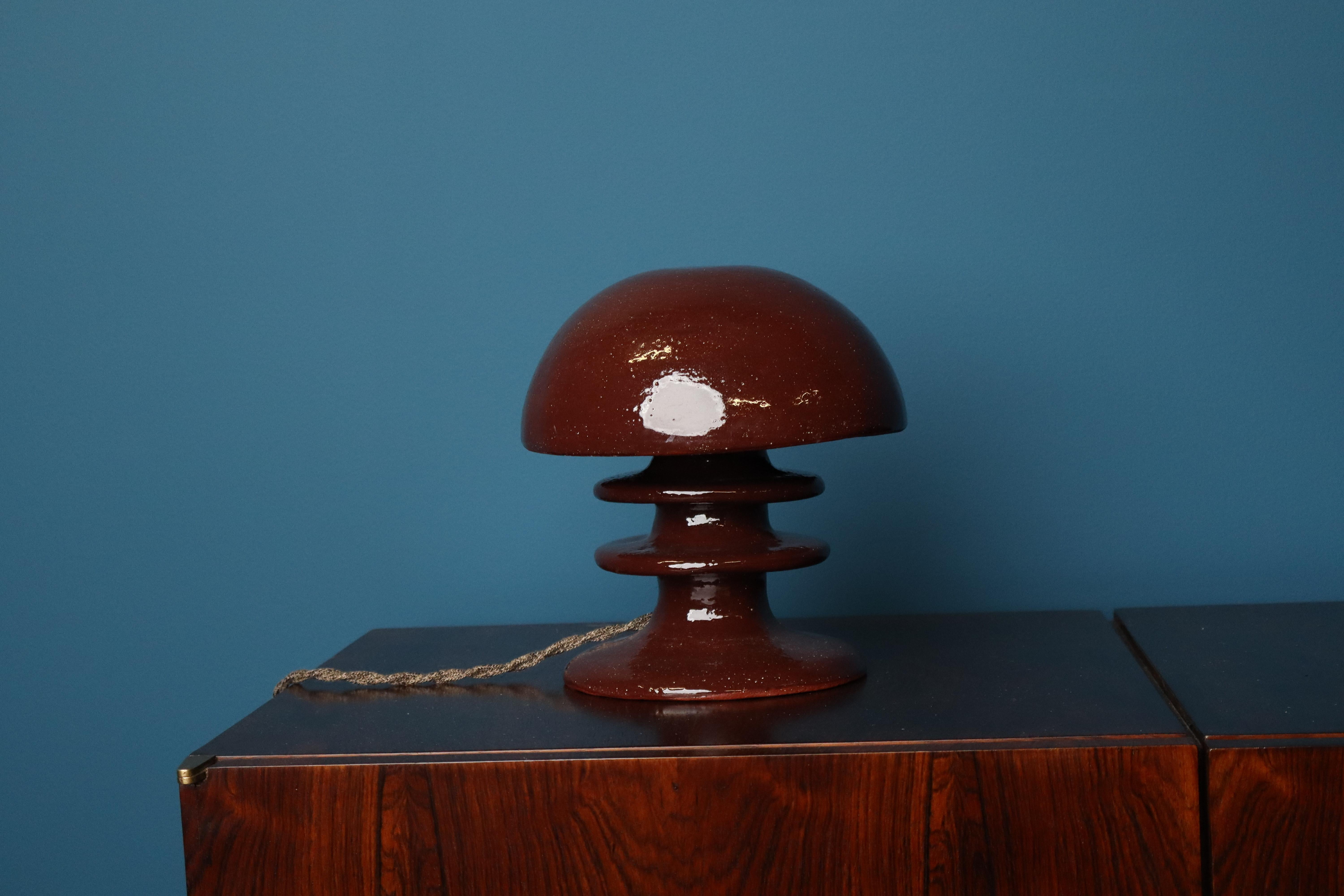 Esta elegante lámpara de mesa de la colección Pachamama de Mariela Cerámica tiene una pantalla de cerámica hecha a mano en Bélgica y acabada con un esmalte de tonos naturales. La pieza evoca una presencia tranquila y orgánica. Su superficie
