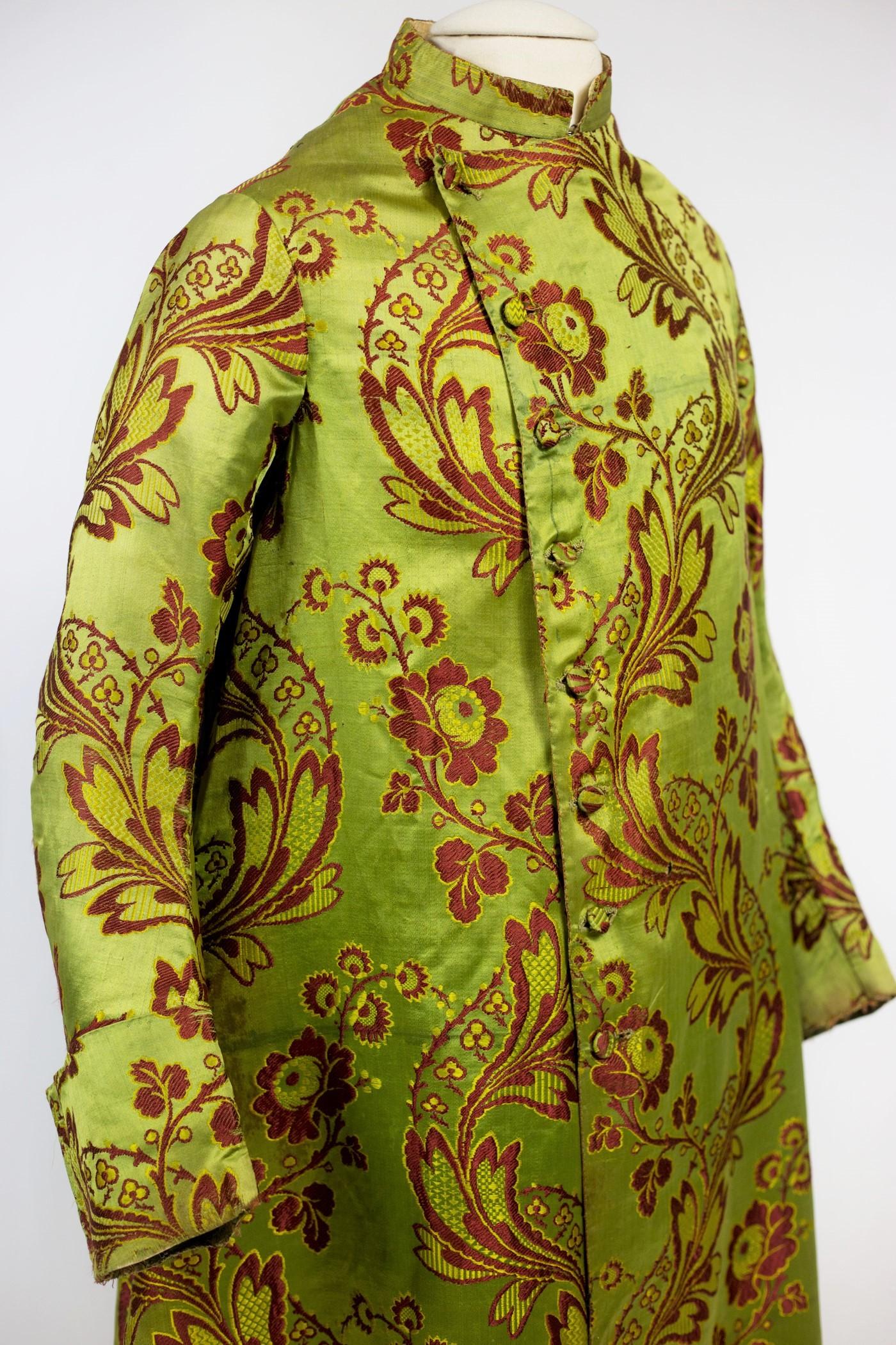 Circa 1750- 1770
France

A Museum piece. Banyan in green-yellow brocaded satin (5-end satin) with en rivière floral decoration whose pattern is made of four lengths of 51 cm wide each. Crossed front and pyramidal cut, closed with eight covered
