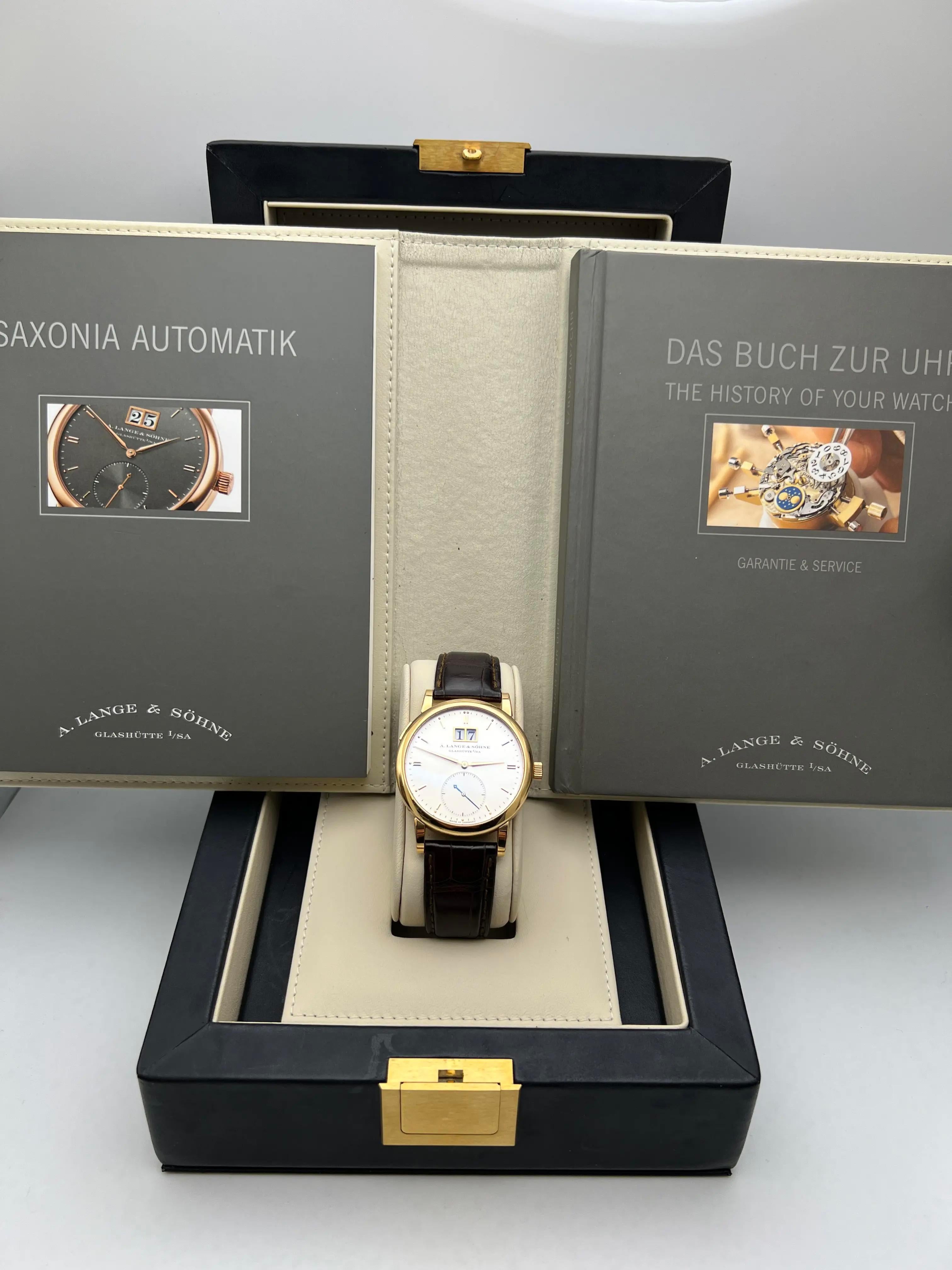 A. Lange & Söhne Saxonia Automatic reference 315.032, featuring a 37mm 18k rose gold case paired with a refined silver dial. The dial showcases rose gold applied hour markers and hands, a date window positioned at 12 o'clock controlled by a push