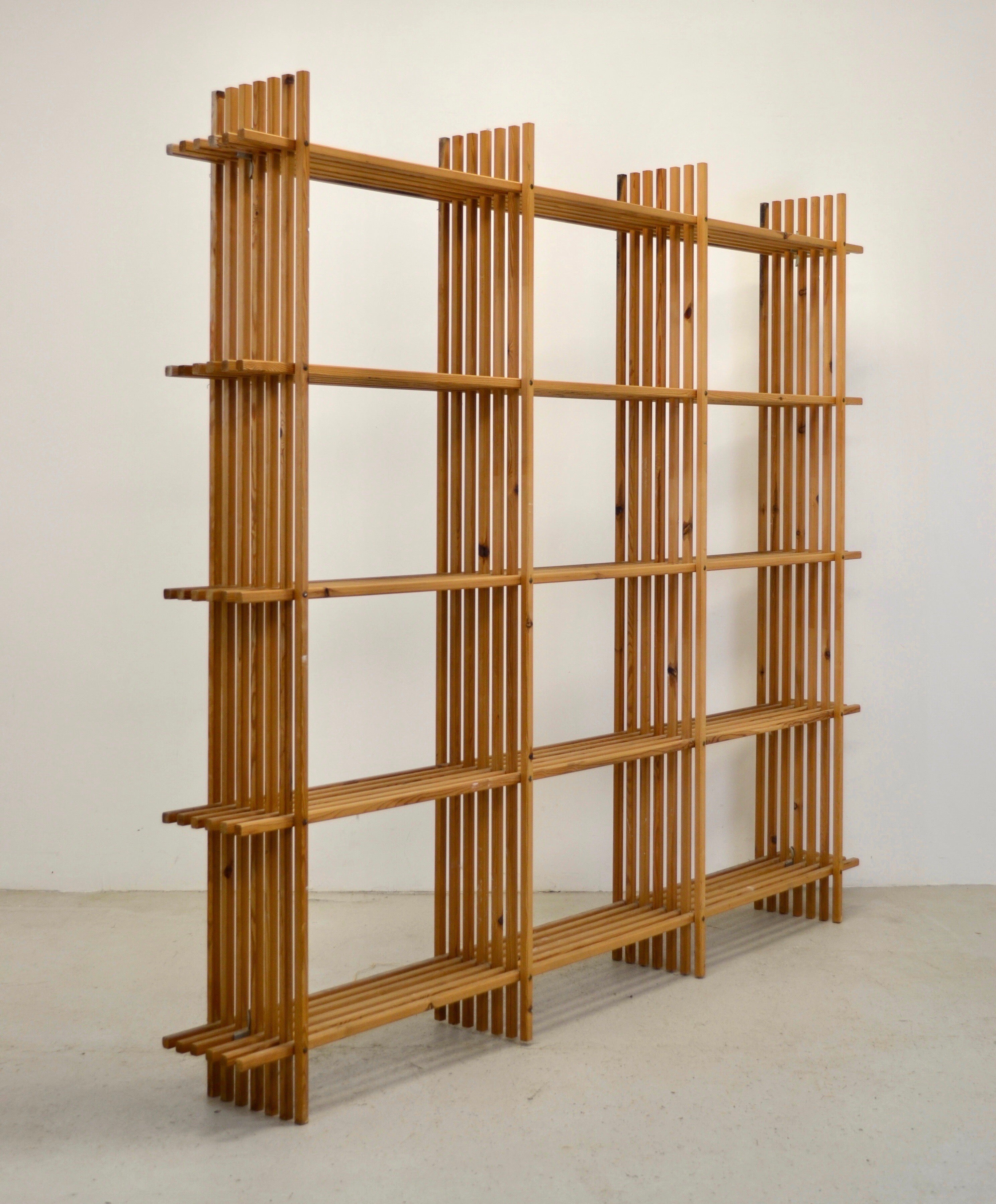 A bookcase or shelves designed in France in the 1960s in larch wood. They are distinguished by remarkable graphic work and striking visual lightness. The pieces are assembled using through rods and held in place by a clever metal system, as shown in