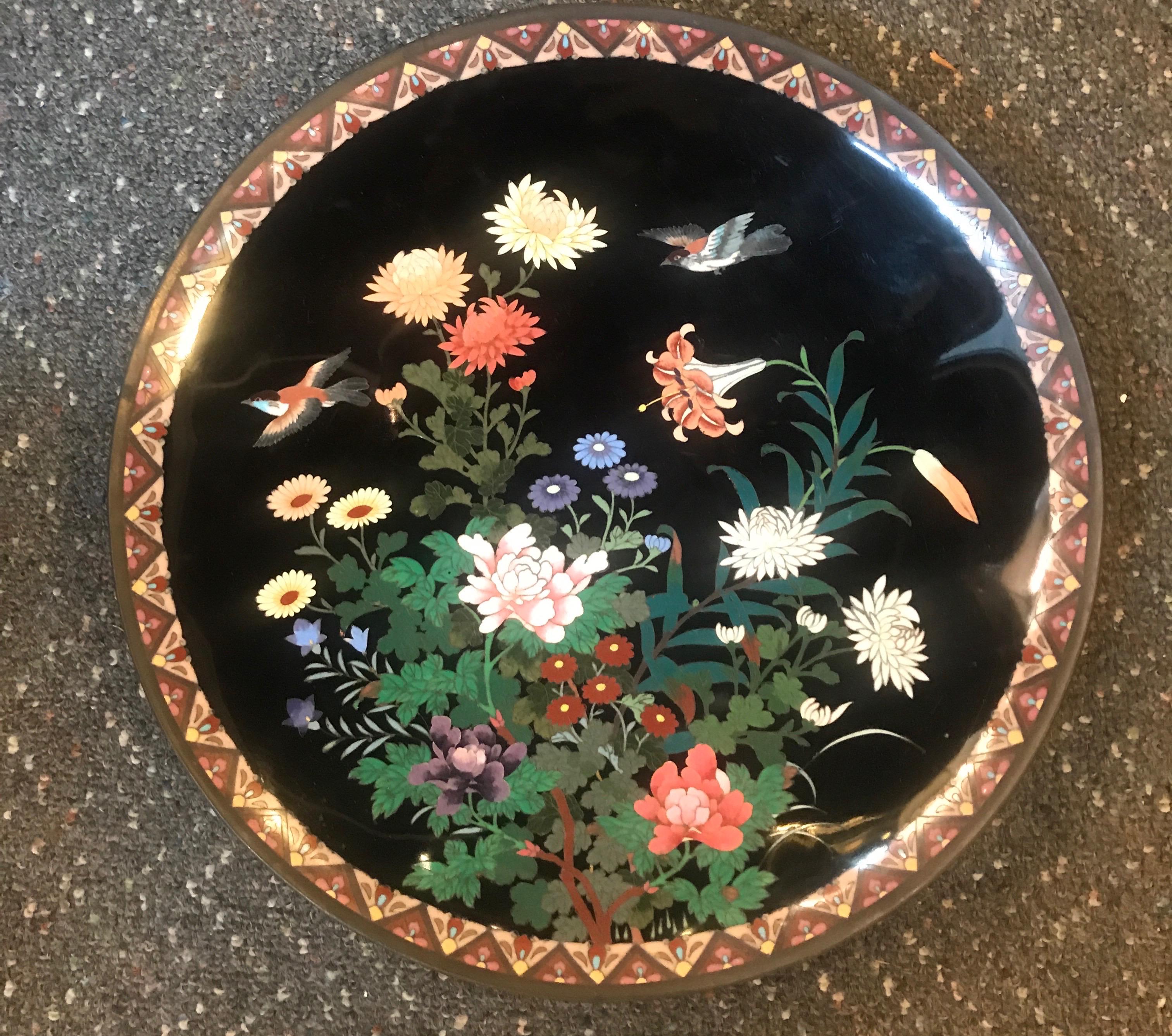 Ravissant grand chargeur japonais en émail cloisonné Période Meiji (1868-1912). Mesure : Large 14 pouces.

Émail complexe sur laiton cloisonné représentant un motif floral et feuillu coloré avec des oiseaux volants entourés d'une bordure à motifs