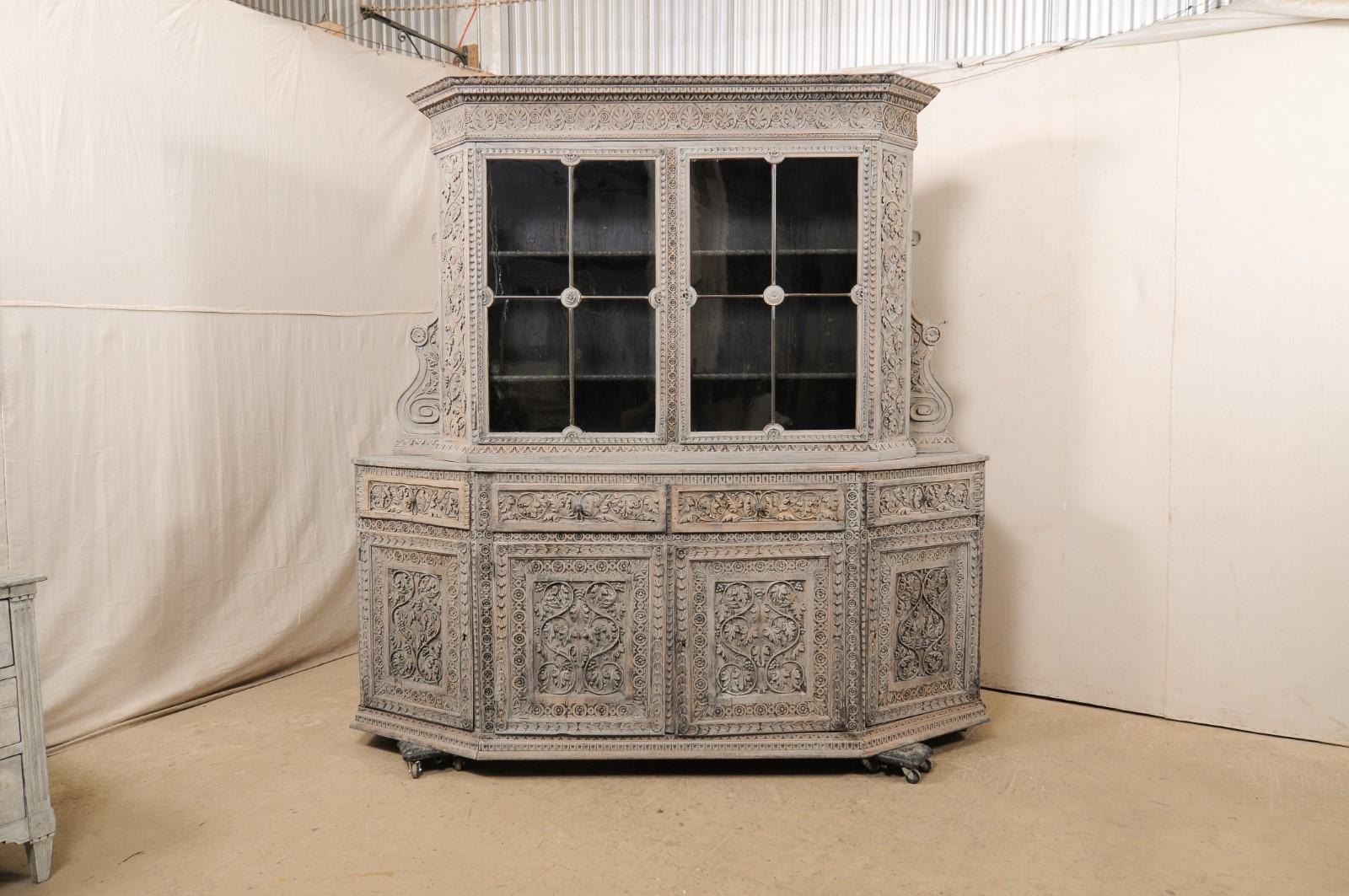 A positively gorgeous, large-sized, Italian hand-carved wood cabinet, with upper glass display, from the 18th century. This antique cabinet from Italy features an elaborately carved foliage and floral motif design-with particular emphasis beneath