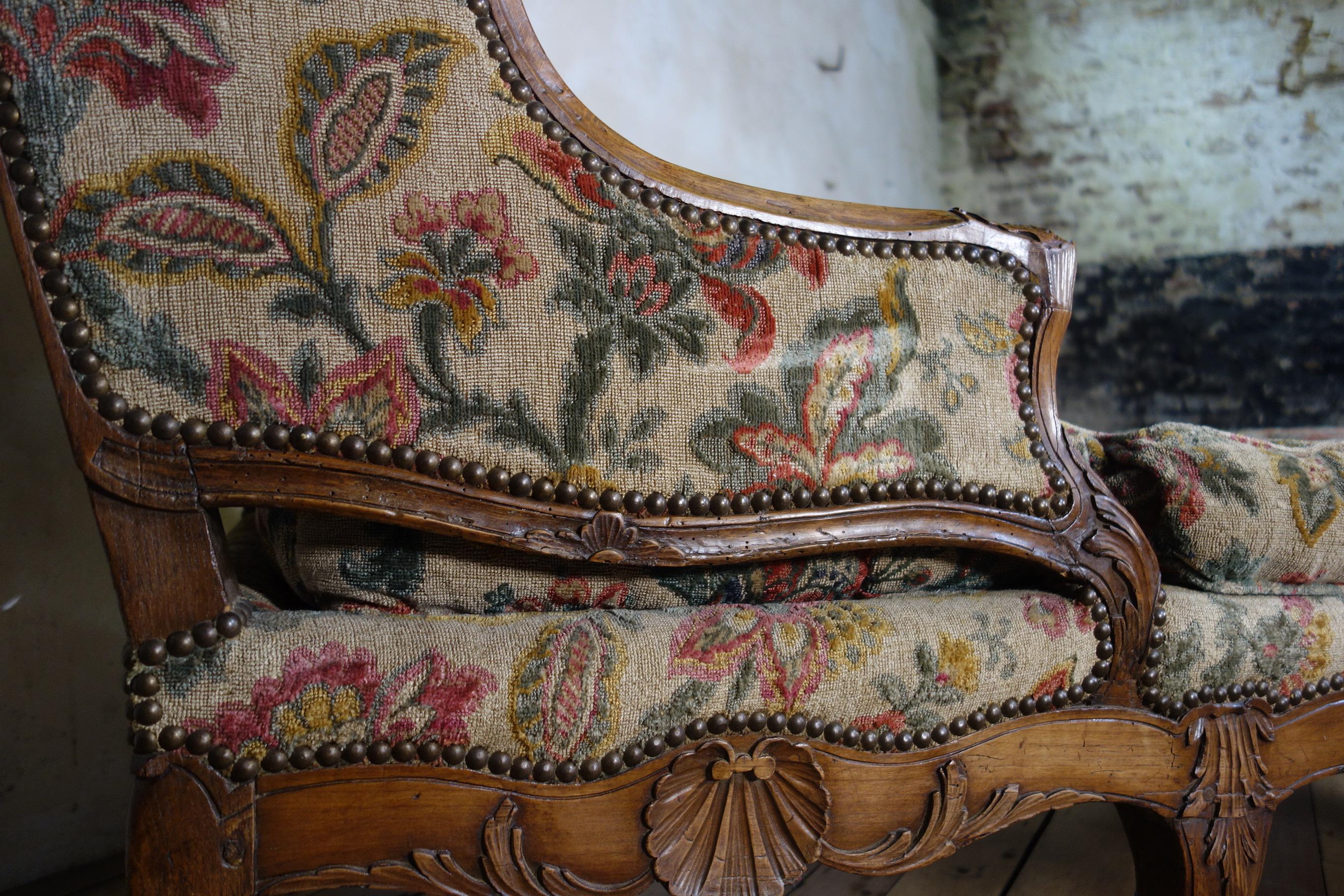 A large scale 18th century French chaise longue, raised on carved cabriole legs demonstrating scallop carvings to the serpentine seat rail. Upholstered in an extraordinary fabric, displaying rich tones throughout. 
 
Measures: Height 102cm 
Seat