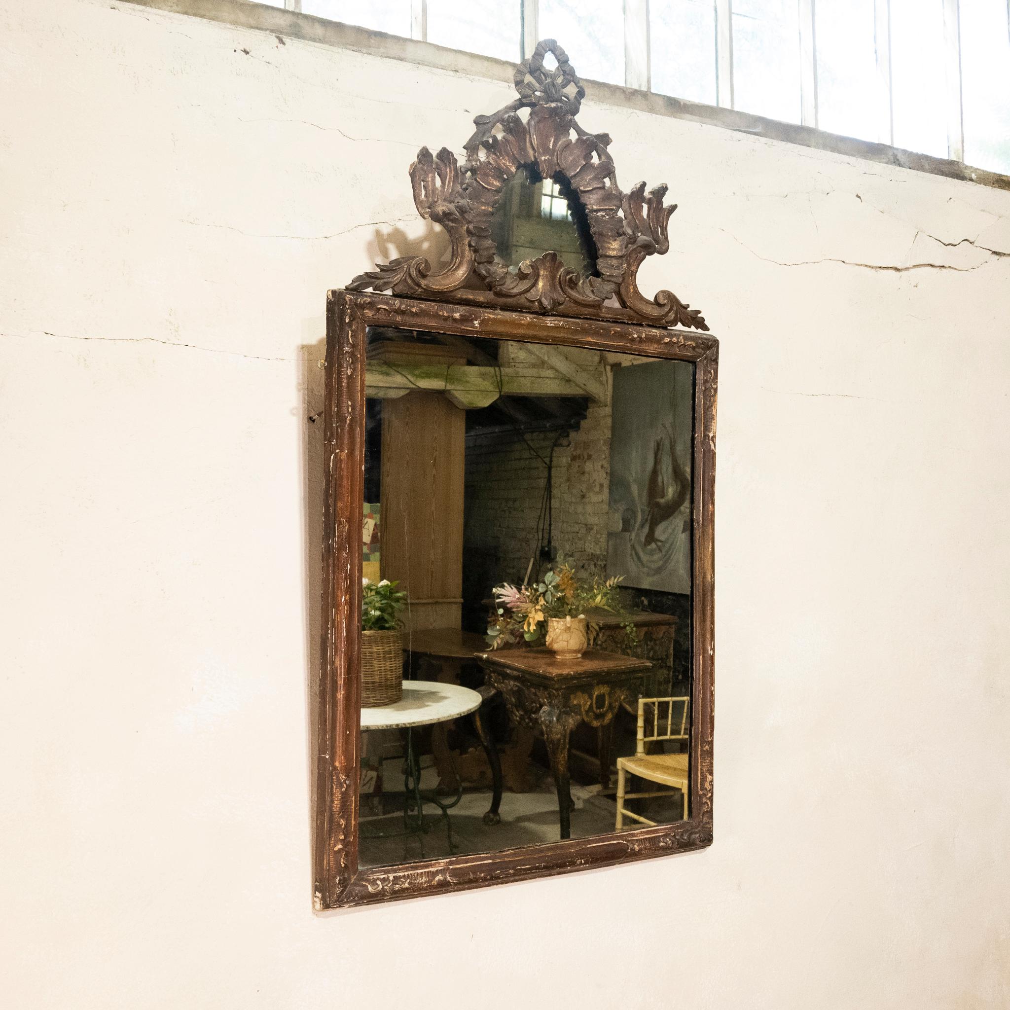 A remarkable 18th-century Italian Rococo period mirror.  Displaying a carved giltwood, and original painted rectangular bead-and-bar frame.  surmounted by a pierced pediment of a round mirror plate and ribbons, supported by C-scrolls. Husking and
