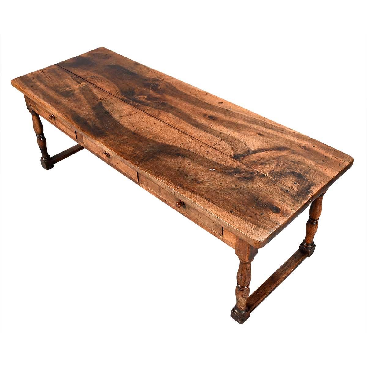 A large 18th Century walnut center (or kitchen) table. The thick, two-board top has a striking grain to the timber. The three frieze drawers are fitted with wooden knob handles. The baluster-turned legs are connected by low end stretchers. Terrific