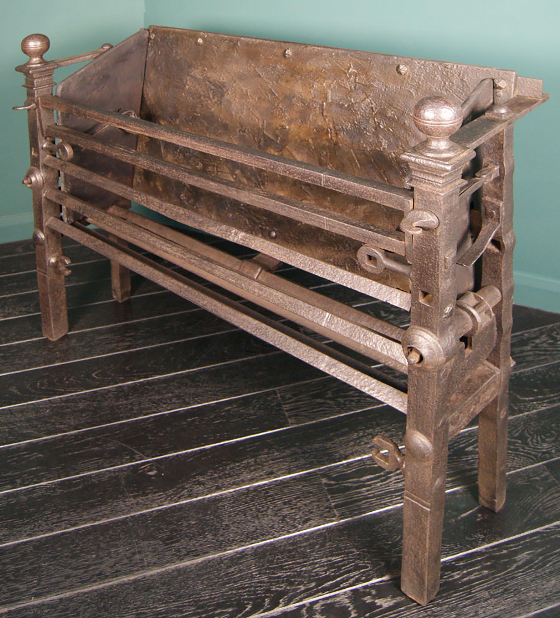 A large 18th century wrought-iron kitchen range from Allerton Castle in Yorkshire. The iron range has a hinged top fire bar, three lower fire bars set on angle, between robust uprights topped with sphere finials. The hob-sides are fixed; but would